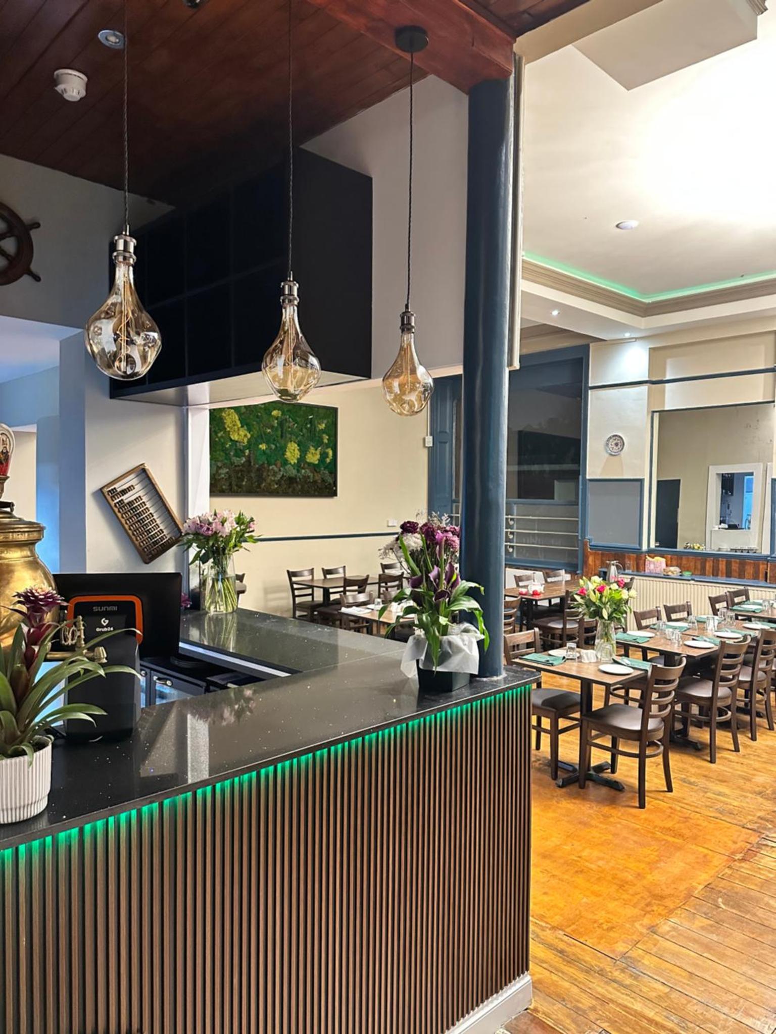 a restaurant with a bar with tables and chairs at Green Ariana Hotel - near Wembley and central London in London