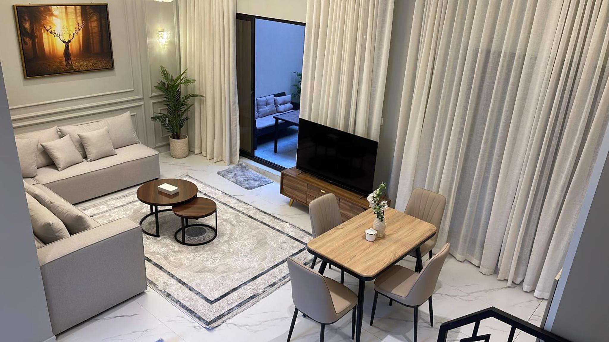 a living room with a television and a table and chairs at Al Rayaan Villa in Juffair