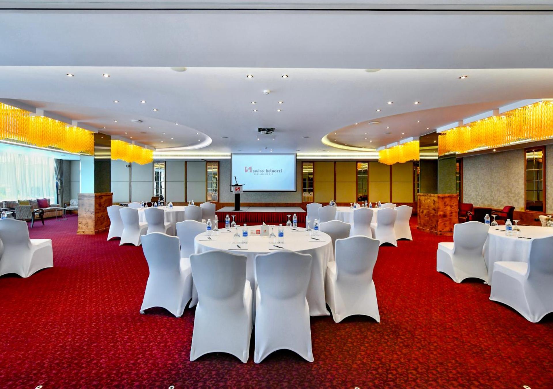 a conference room with white tables and chairs and a screen at Swiss-Belhotel Seef Bahrain in Manama +61 photos
