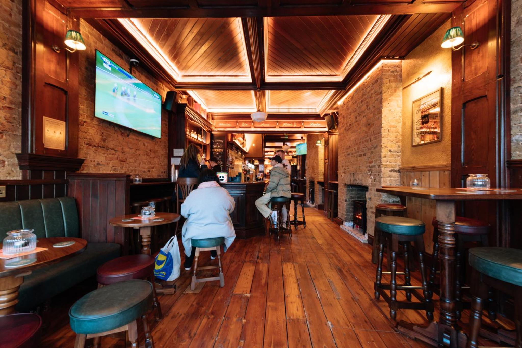 two people sitting at a bar in a restaurant at The Crown Pub & Guesthouse in London