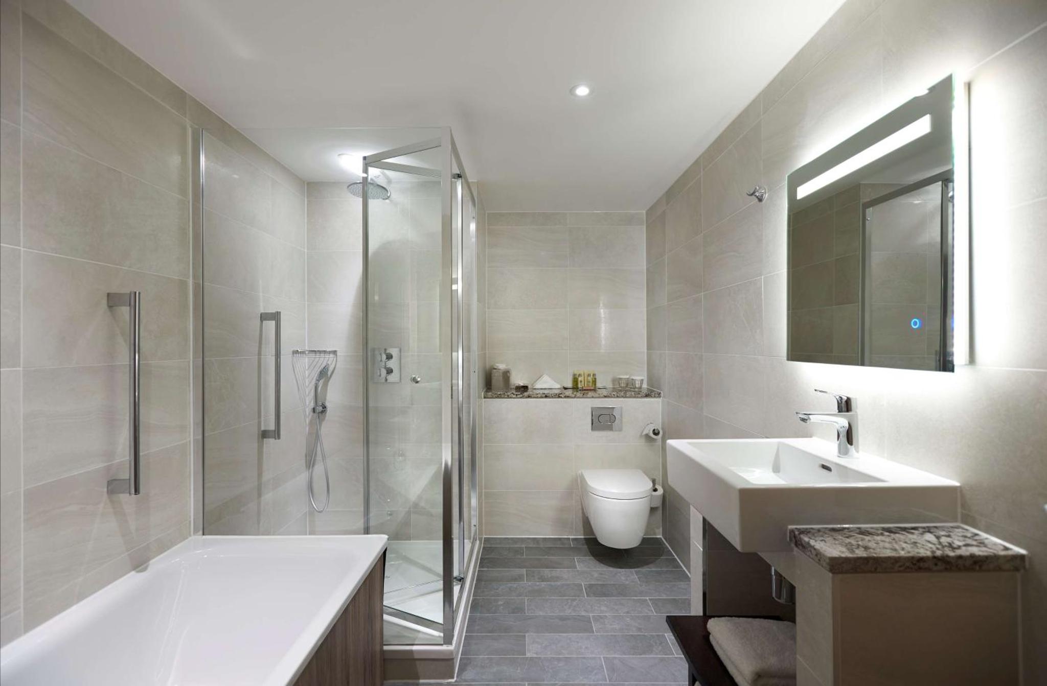 a bathroom with a shower and a sink and a toilet at DoubleTree By Hilton London Excel in London