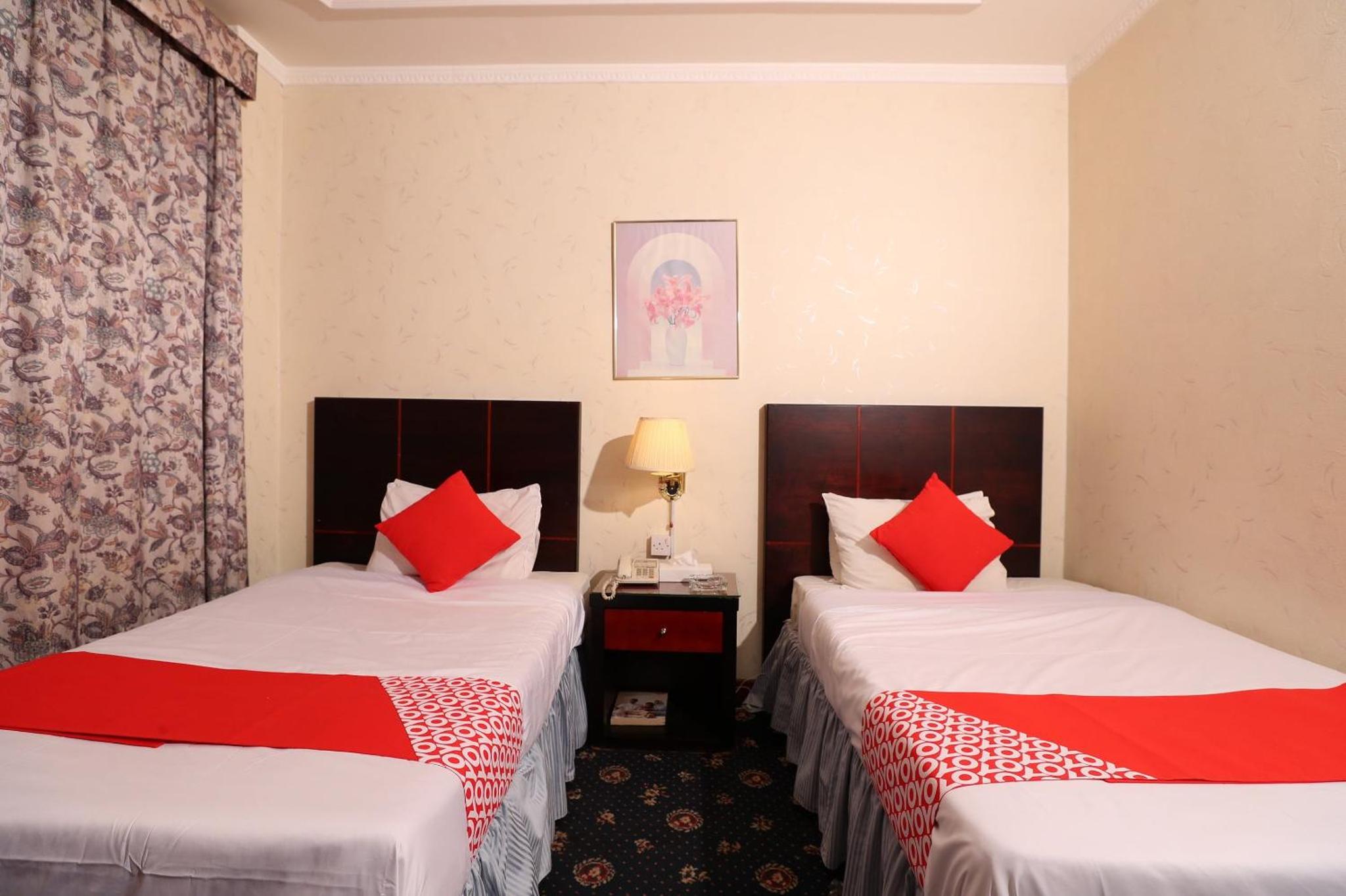 two beds in a hotel room with red pillows at OYO 112 Semiramis Hotel in Manama