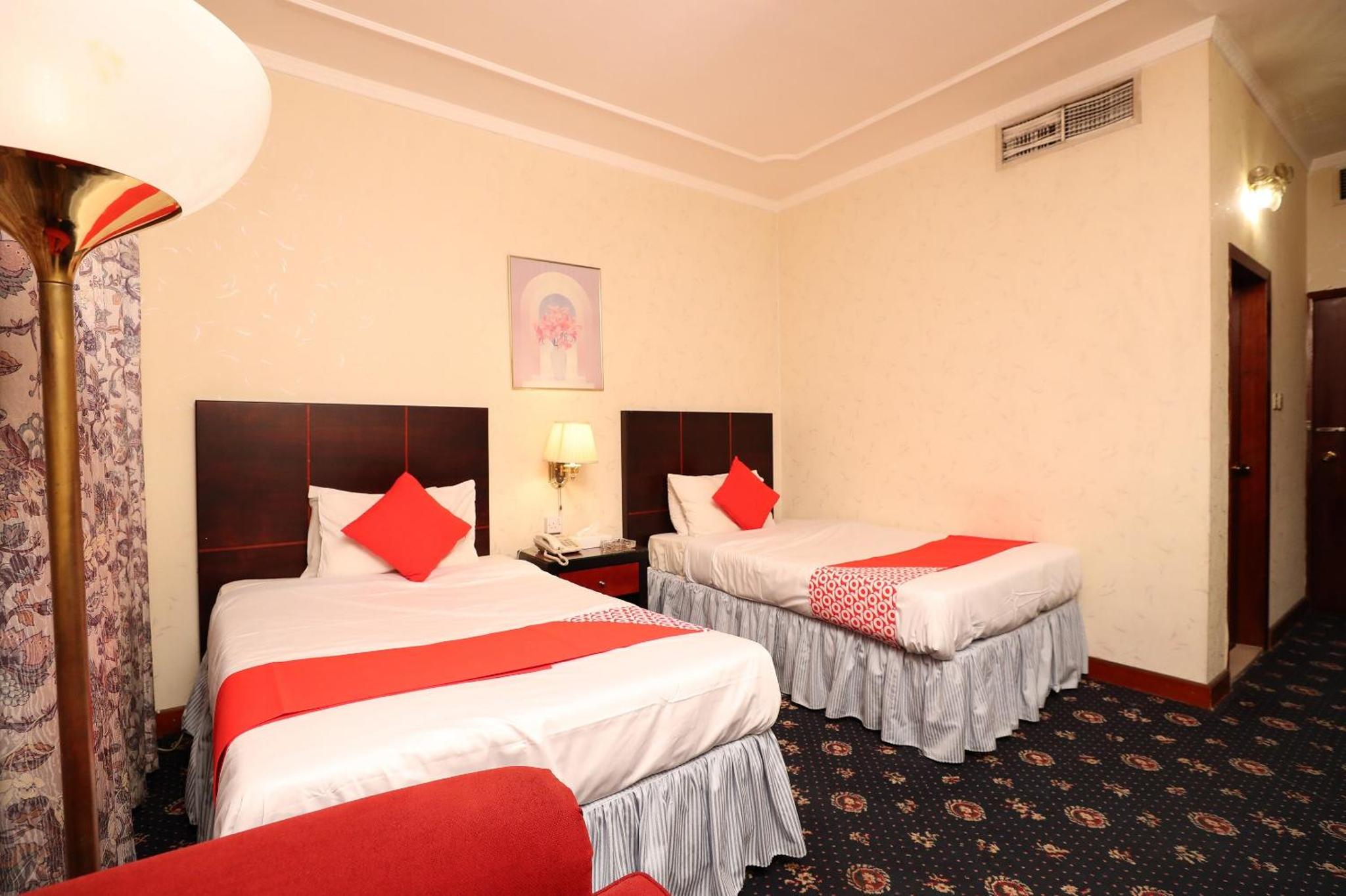 a hotel room with two beds with red pillows at OYO 112 Semiramis Hotel in Manama