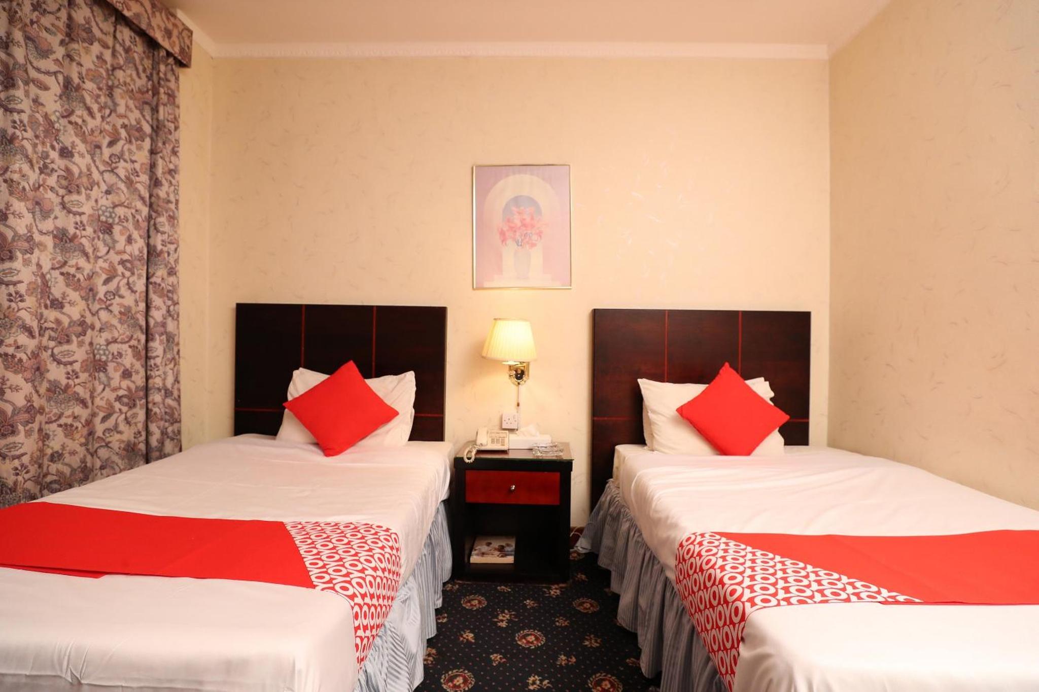 two beds in a hotel room with red pillows at OYO 112 Semiramis Hotel in Manama