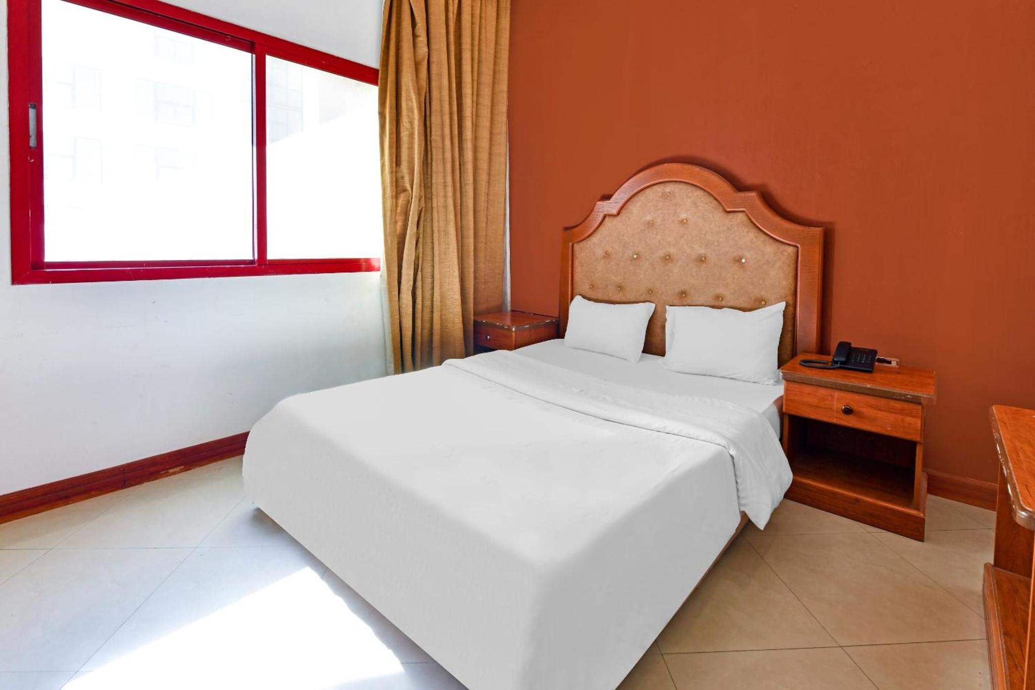 a bedroom with a large white bed and a window at OYO 118 Revira Hotel in Manama