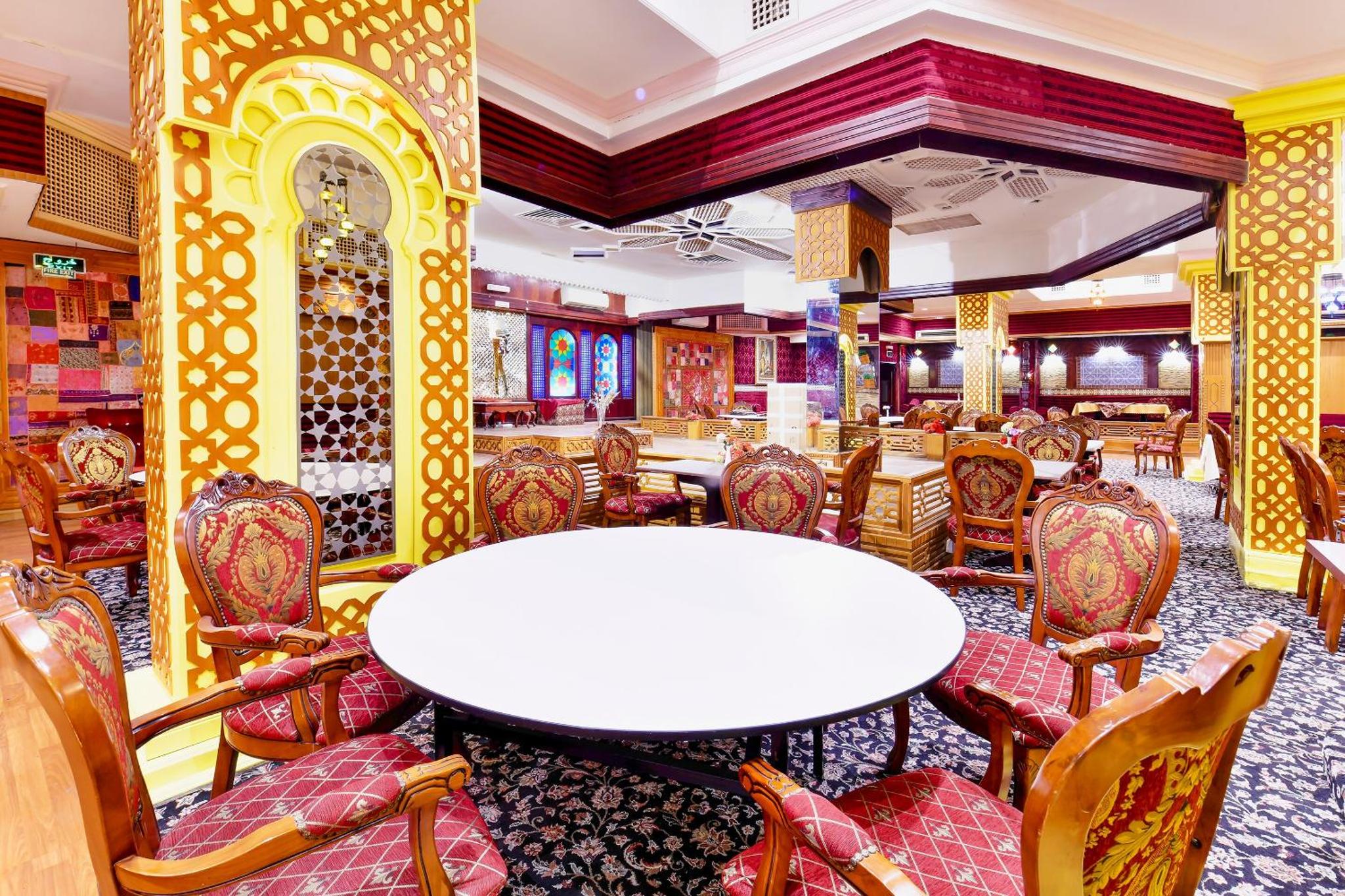 a dining room with a white table and chairs at Capital O 125 Moon Plaza Hotel in Manama +25 photos