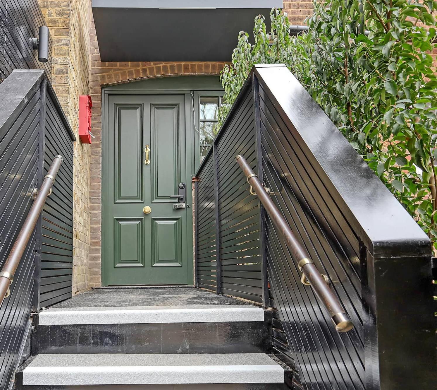 a green door on a brick building with stairs at The Carlton Tavern Hotel in London