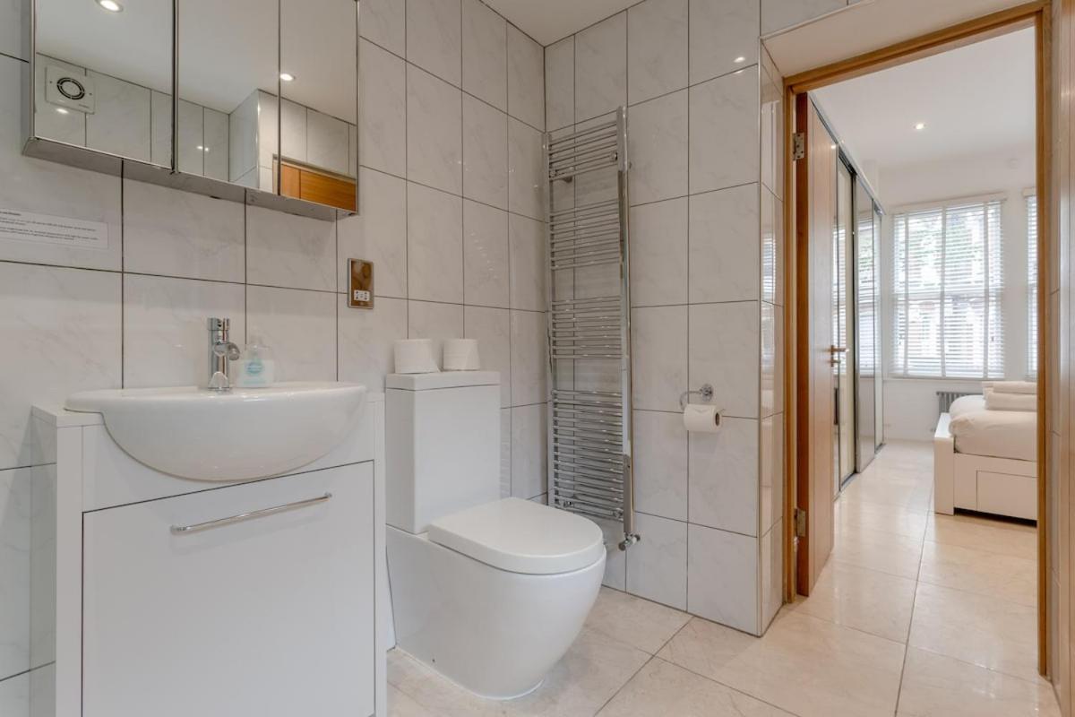 a white bathroom with a toilet and a sink at Bright Modern Large 1 Bed Flat in Battersea Clapham Junction in London