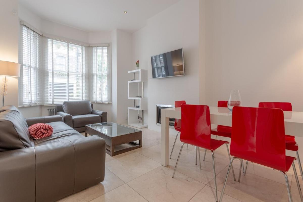 a living room with a couch and a table and red chairs at Bright Modern Large 1 Bed Flat in Battersea Clapham Junction in London