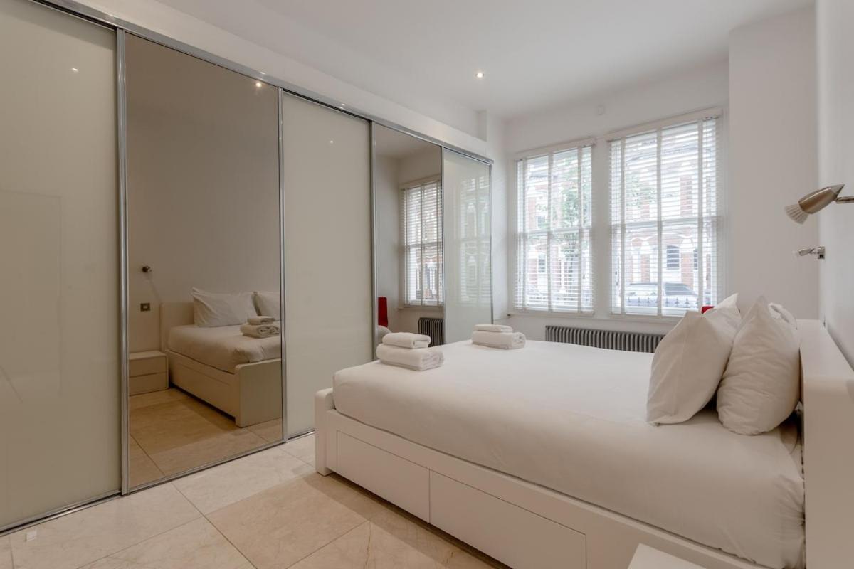 a white bedroom with a large bed and a mirror at Bright Modern Large 1 Bed Flat in Battersea Clapham Junction in London