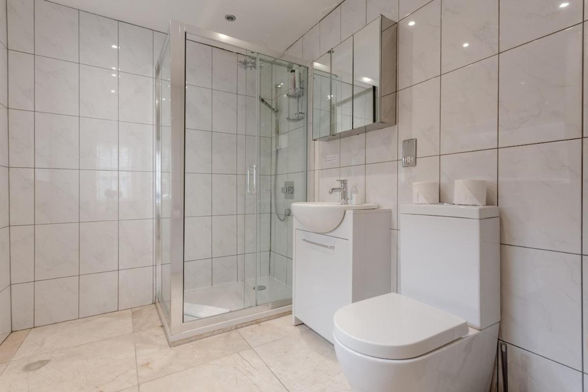 a white bathroom with a toilet and a shower at Bright Modern Large 1 Bed Flat in Battersea Clapham Junction in London +14 photos