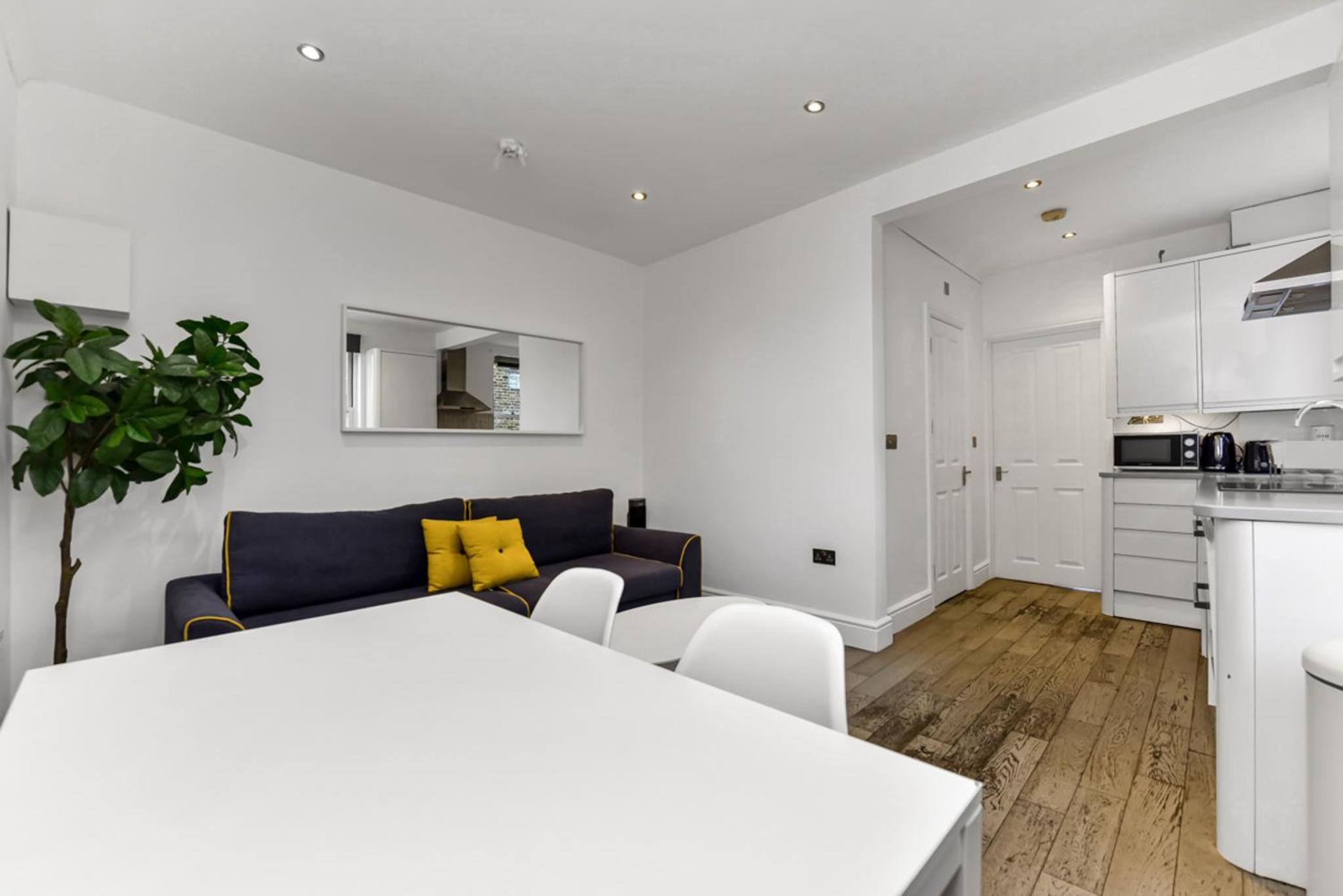 a white living room with a couch and a table at Central, modern 1 Bed in Kennington, Sleeps 4 in London +4 photos