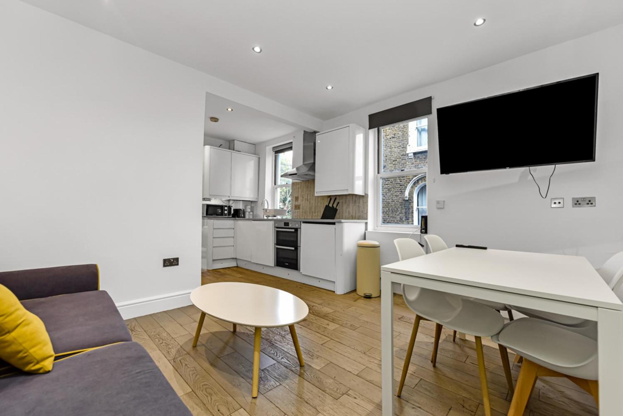 a kitchen and living room with a table and a tv at Central, modern 1 Bed in Kennington, Sleeps 4 in London