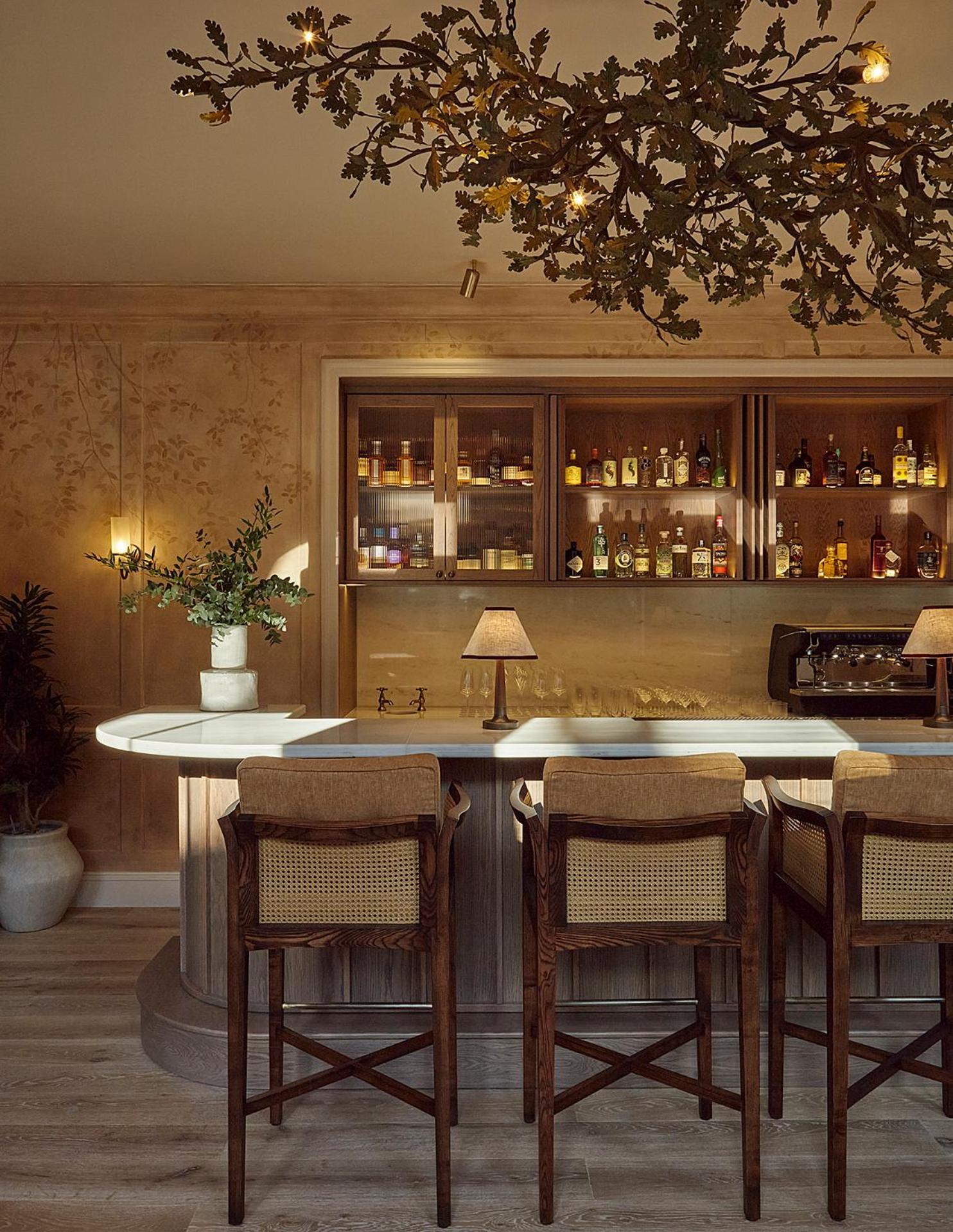 a kitchen with a bar with chairs and a table at Miiro Templeton Garden in London