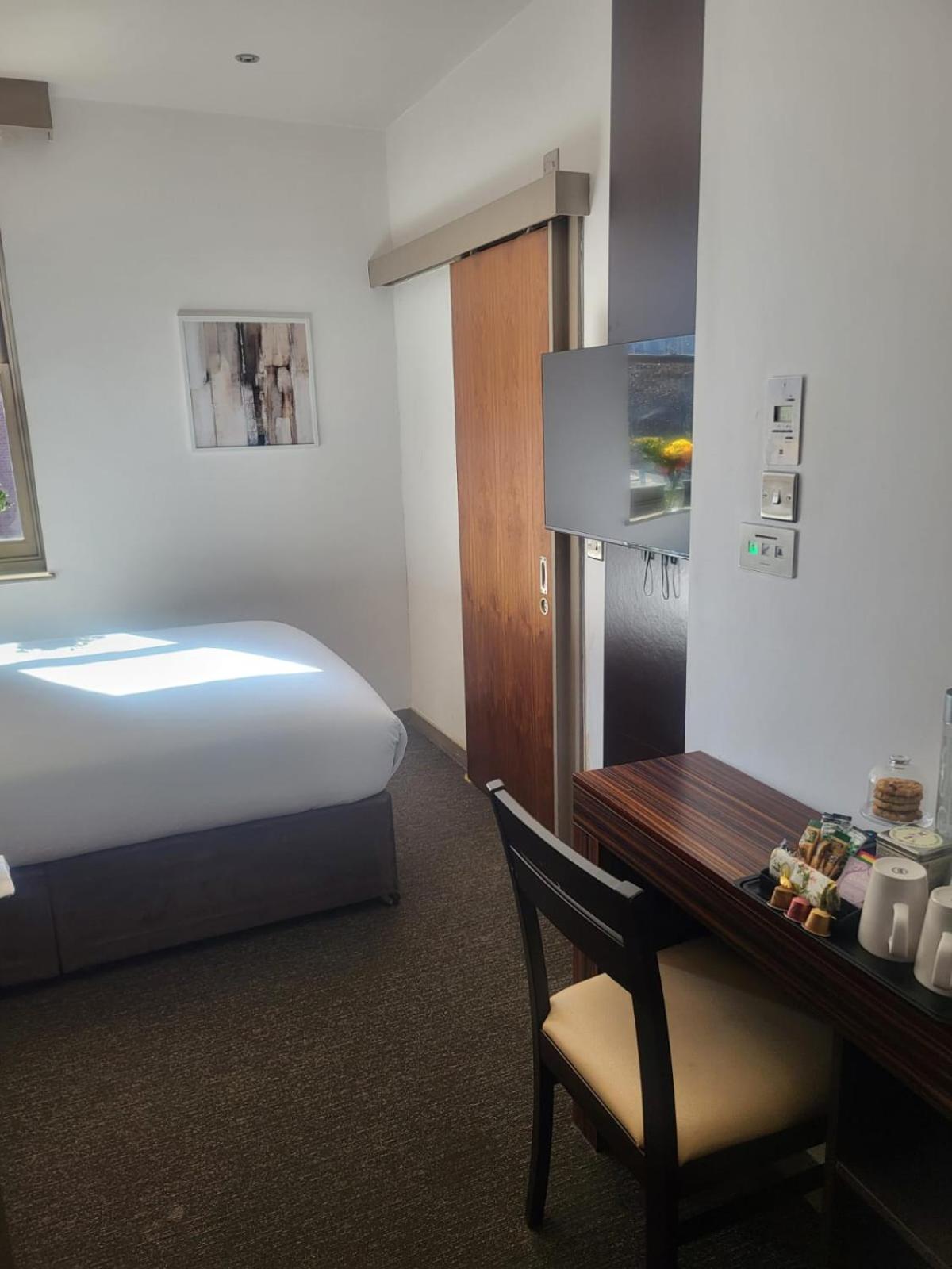 a hotel room with a bed and a table with a chair at Central Boutique Room 302 in London +3 photos