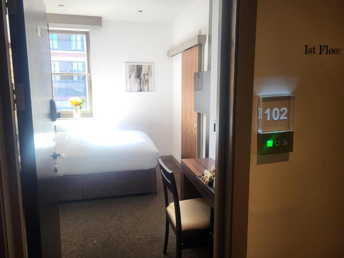 a hotel room with a bed and a table and a clock at Central Boutique Room 302 in London