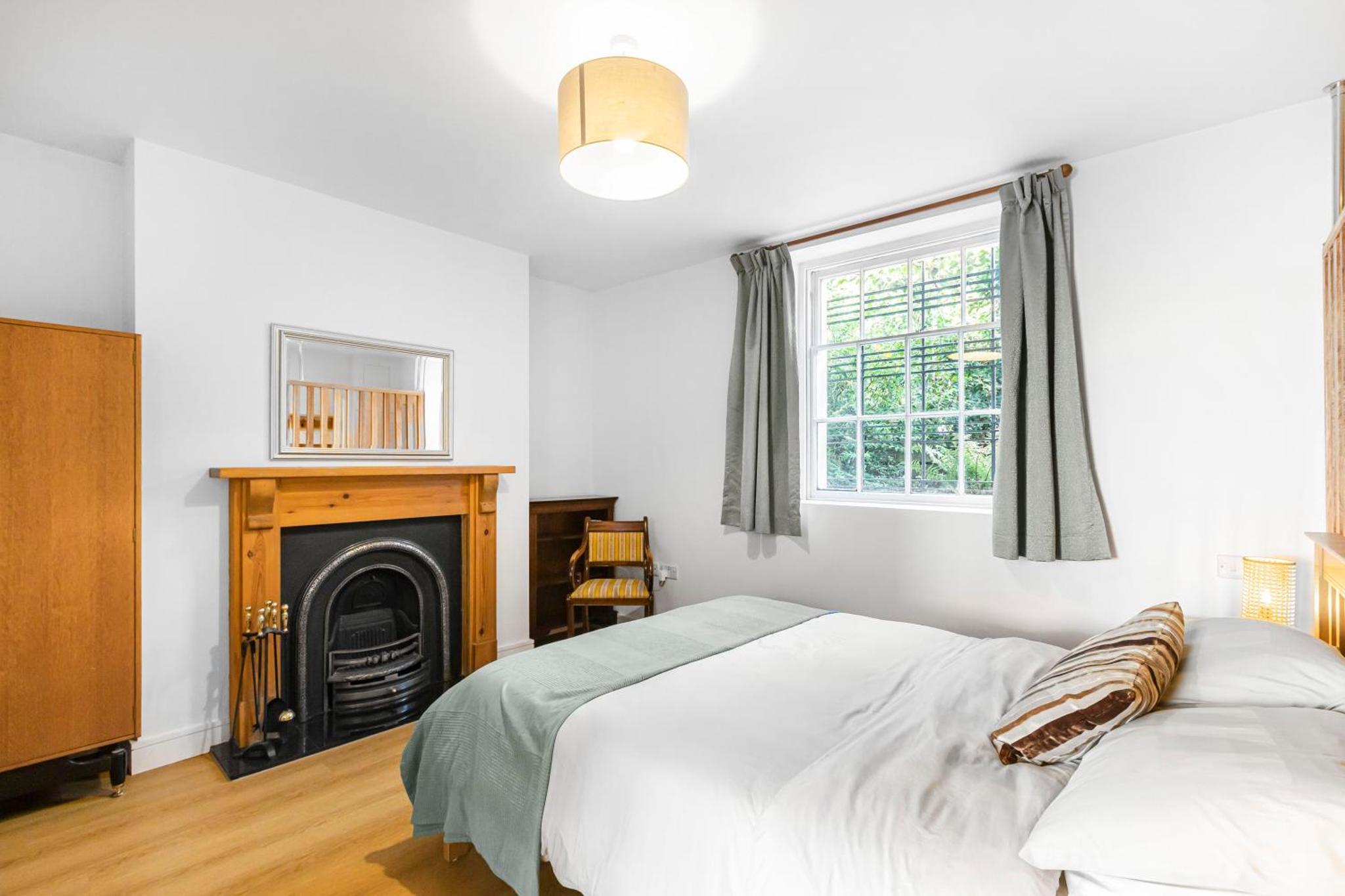 a white bedroom with a bed and a fireplace at Large, quiet flat in Islington in London