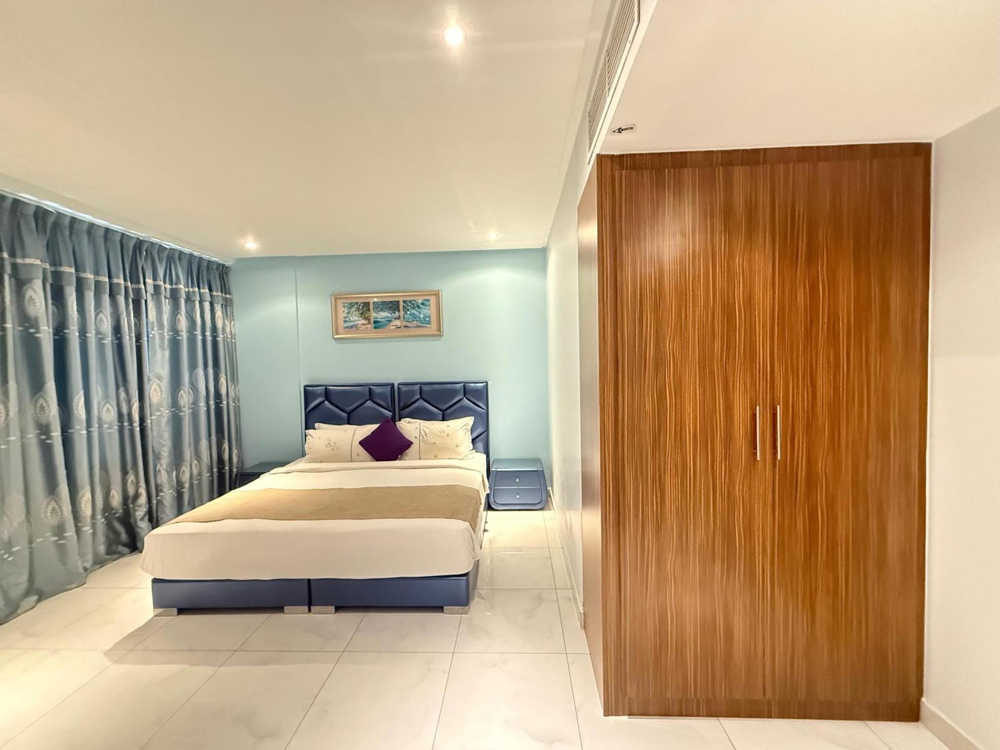 a bedroom with a bed and a wooden closet at Swan Towers Juffair in Manama +27 photos