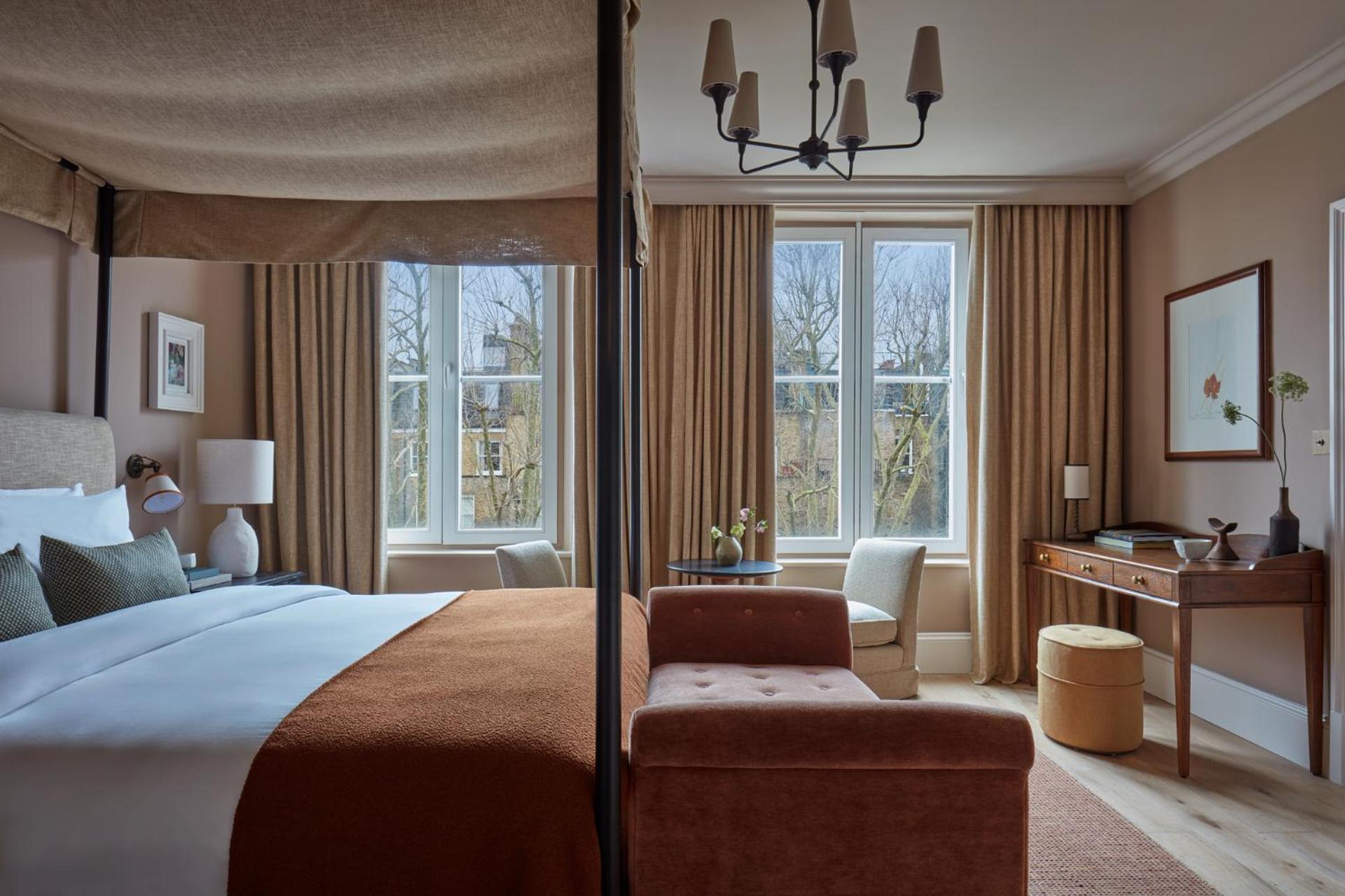 a bedroom with a bed and a desk and windows at Miiro Templeton Garden in London