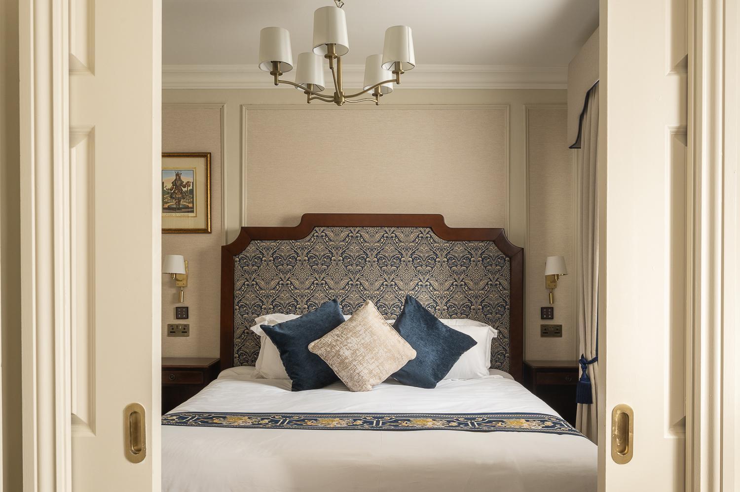 a bedroom with a bed with blue and white pillows at The Leonard Hotel in London
