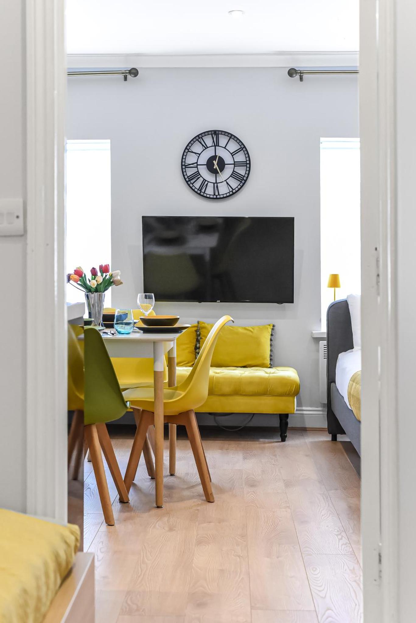 a dining room with a yellow table and a yellow couch at Beautiful Flat On Oxford Street in London +4 photos