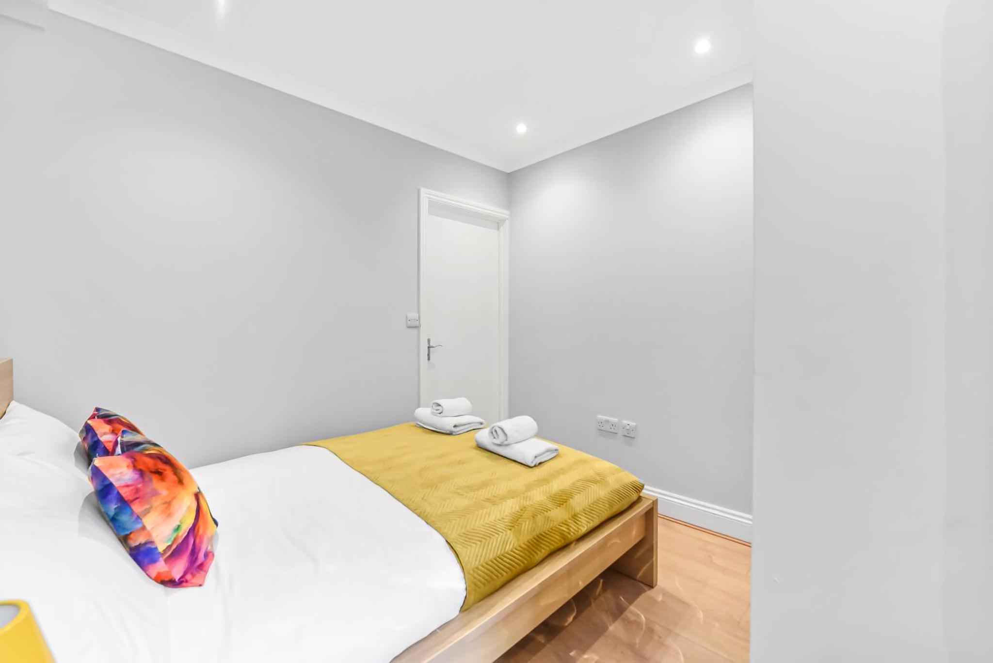 a bedroom with a bed with white walls and wooden floors at Beautiful Flat On Oxford Street in London