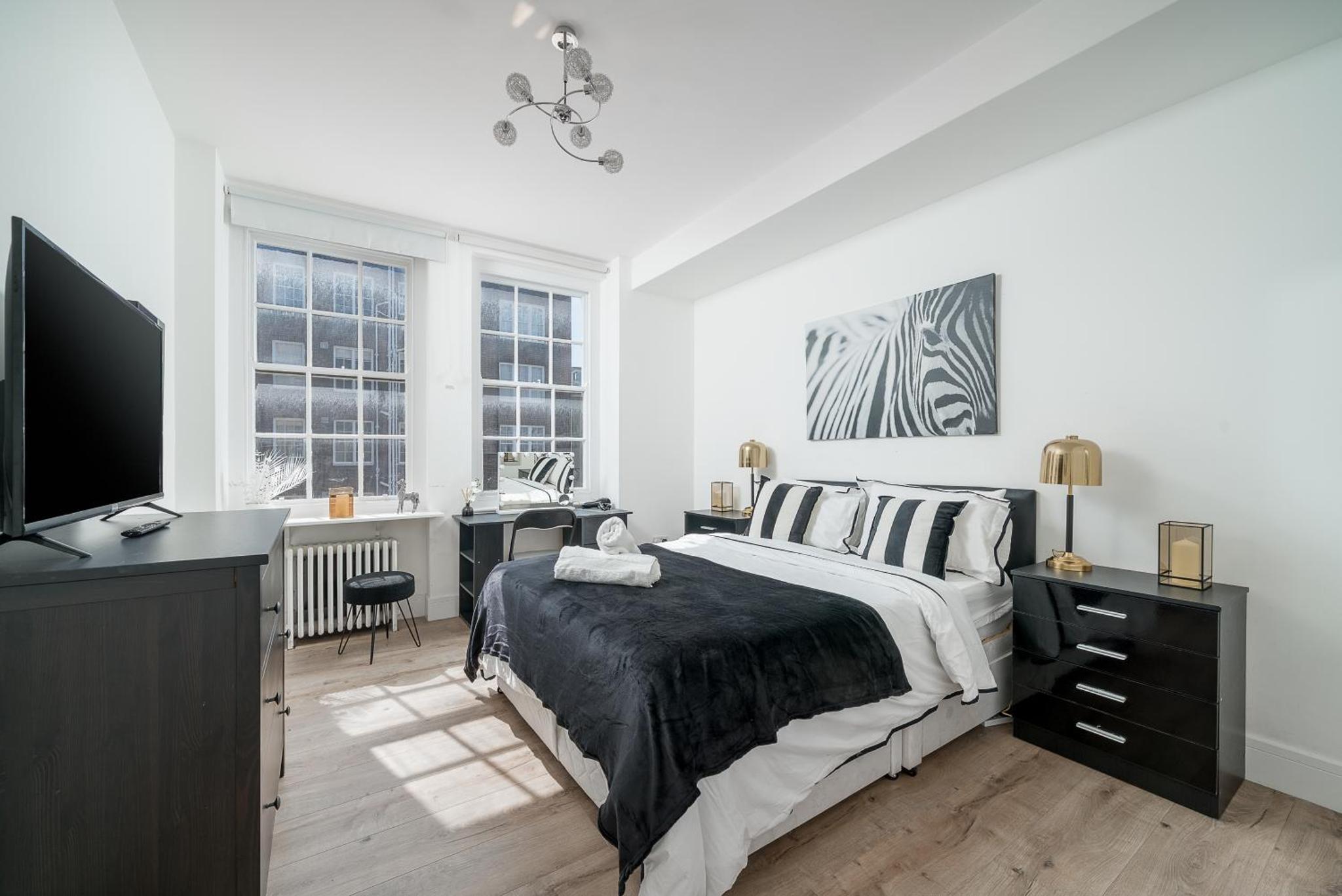 a bedroom with a bed and a desk and a television at Elegant 4 Bed Flat Opposite Hyde Park in London