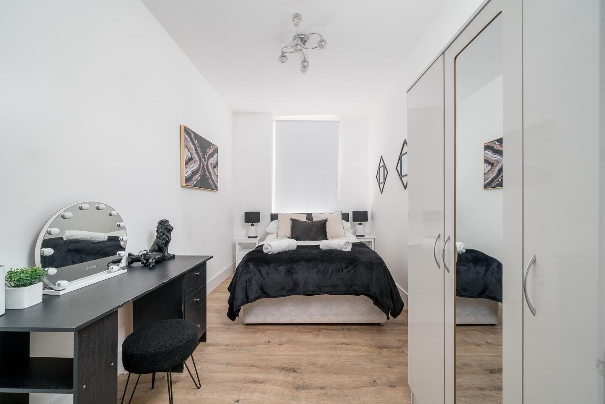 a bedroom with a bed and a desk and a mirror at Elegant 4 Bed Flat Opposite Hyde Park in London