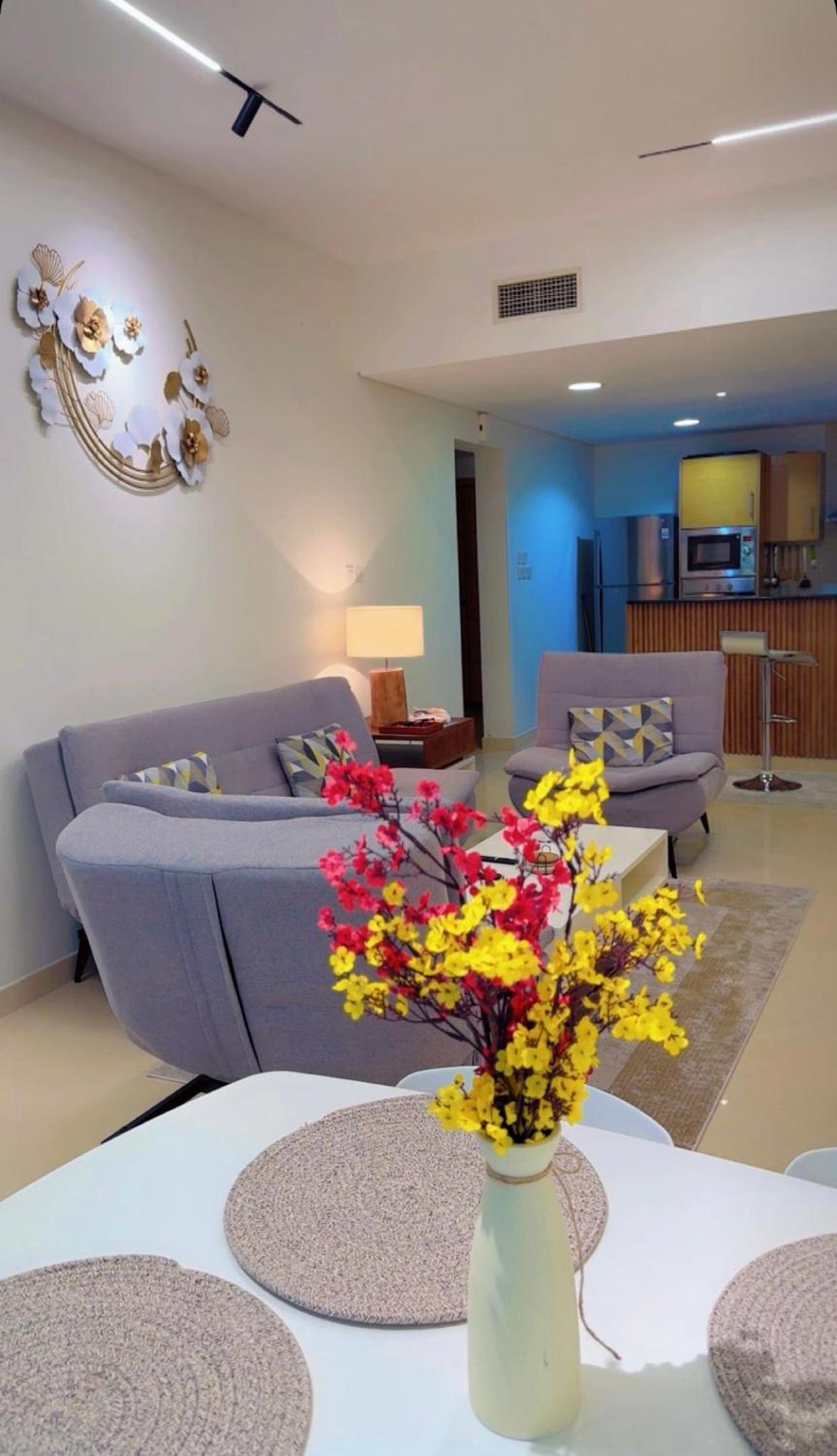 a living room with a couch and a vase with flowers at شقة خاصة in Muharraq