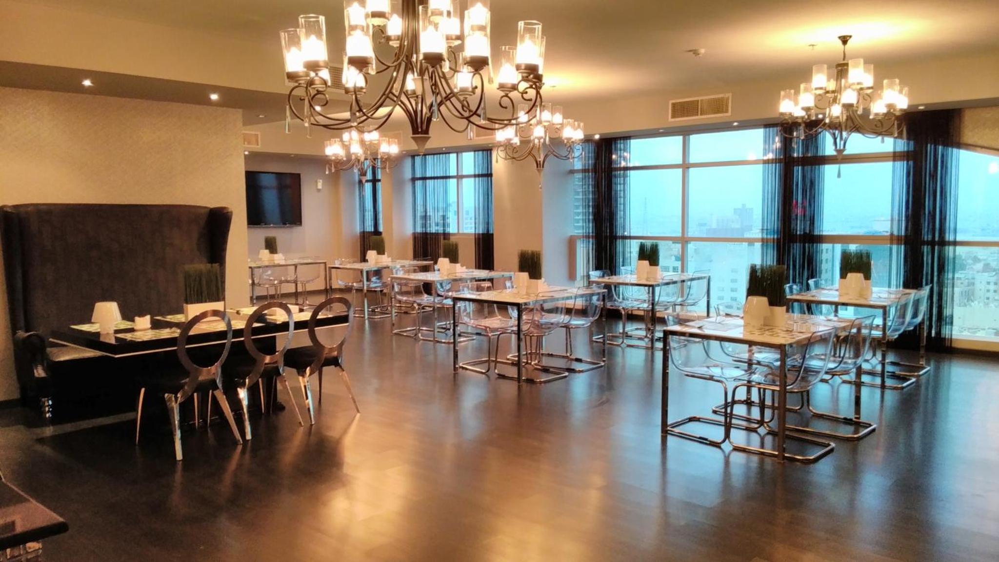 a dining room with tables and chairs and a chandelier at Al Manzil Hotel Bahrain in Juffair +35 photos