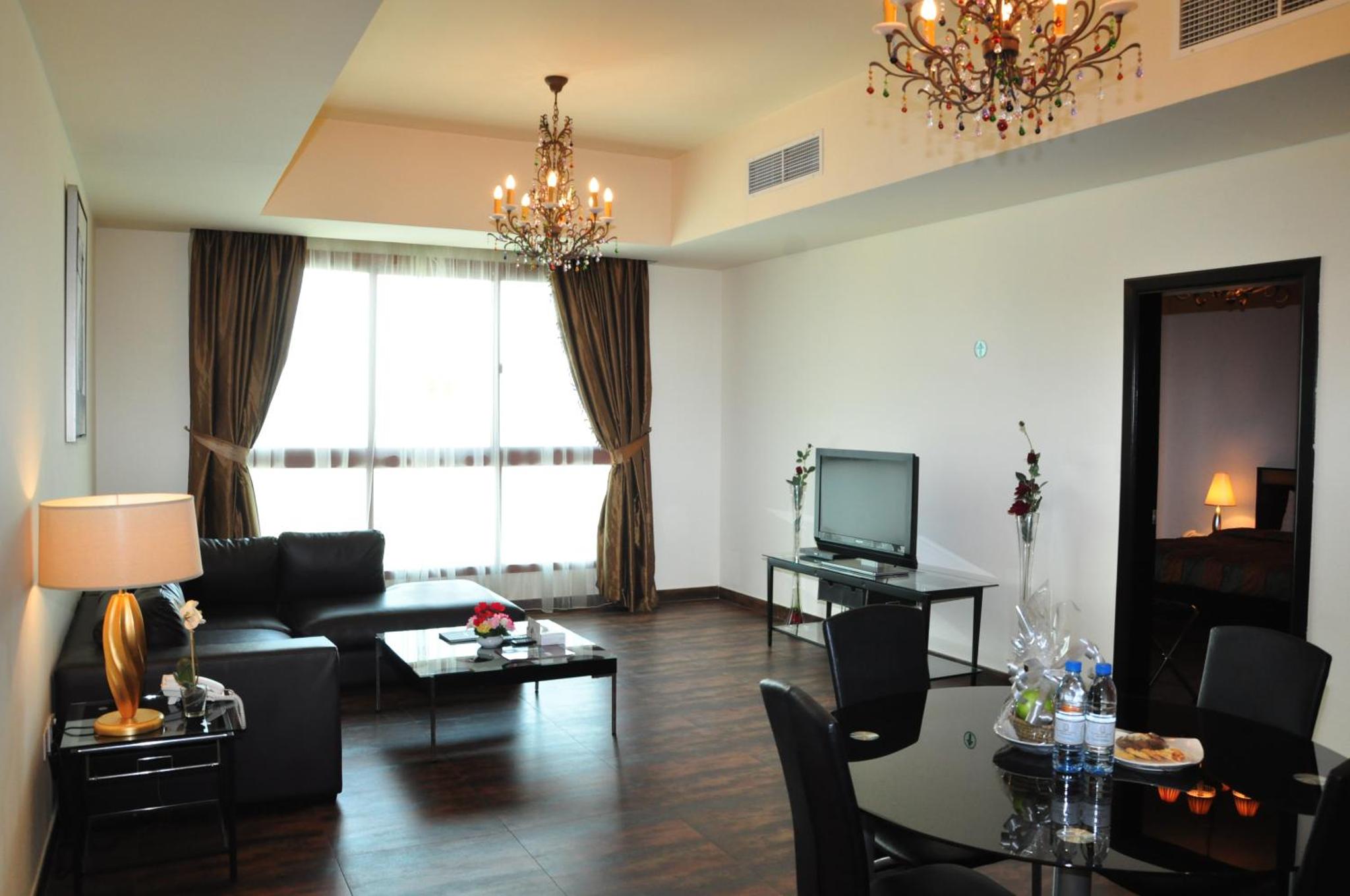 a living room with a couch and a tv at Al Manzil Hotel Bahrain in Juffair