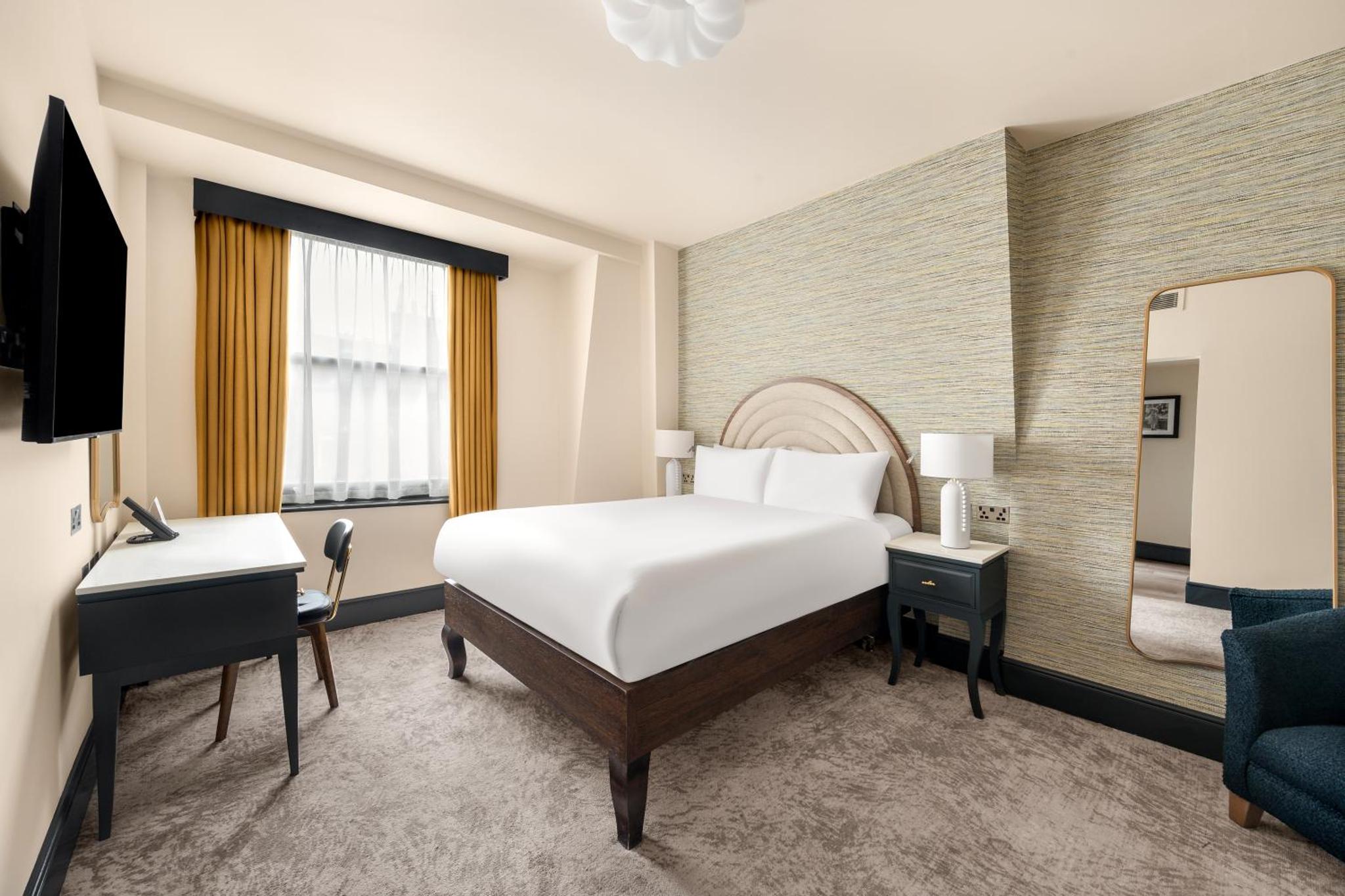 a hotel room with a bed and a desk at Hotel Indigo London - Kensington by IHG in London