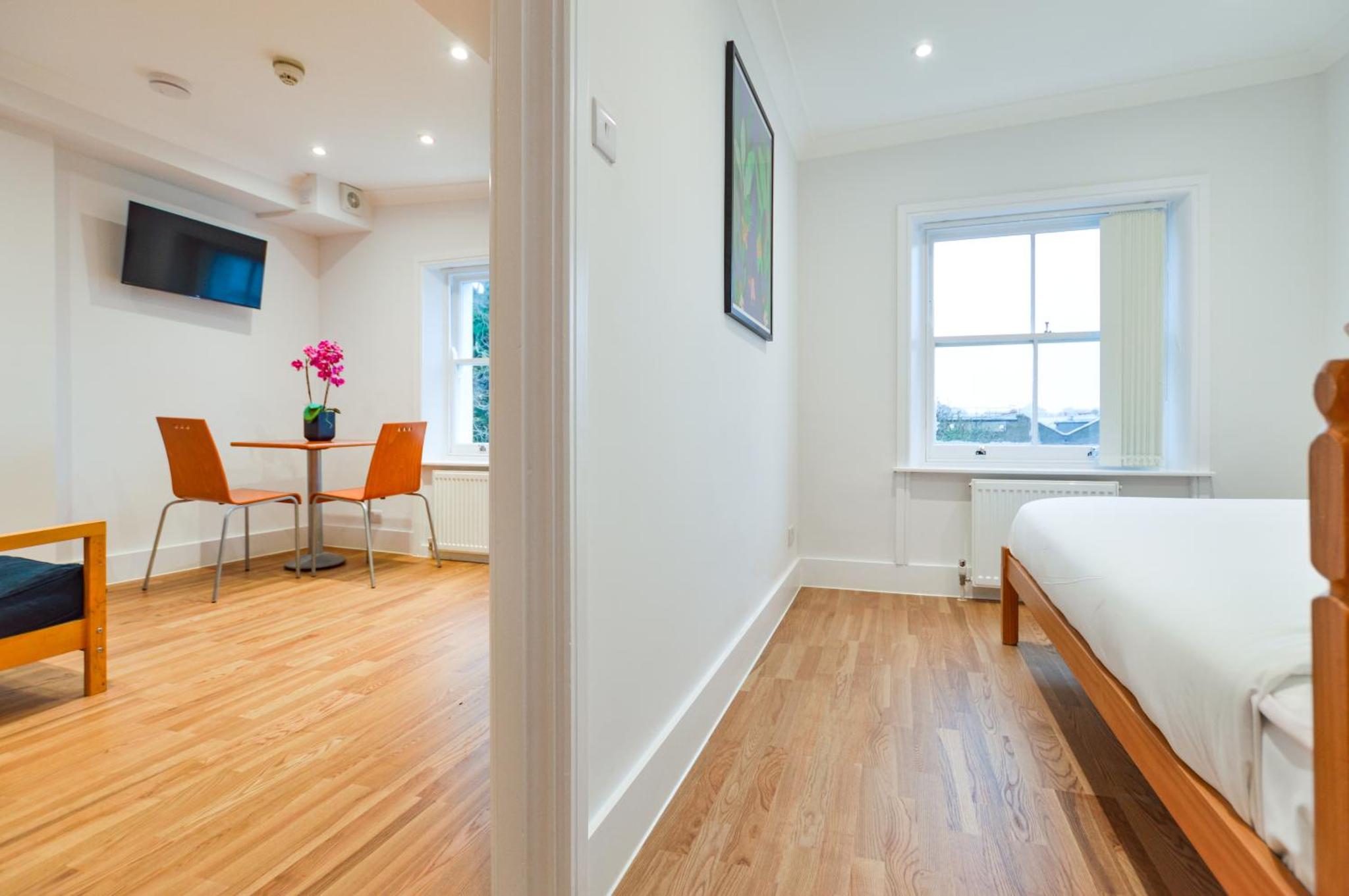 a bedroom with a bed and a desk and a table at Westbourne Crescent Serviced Apartments in London