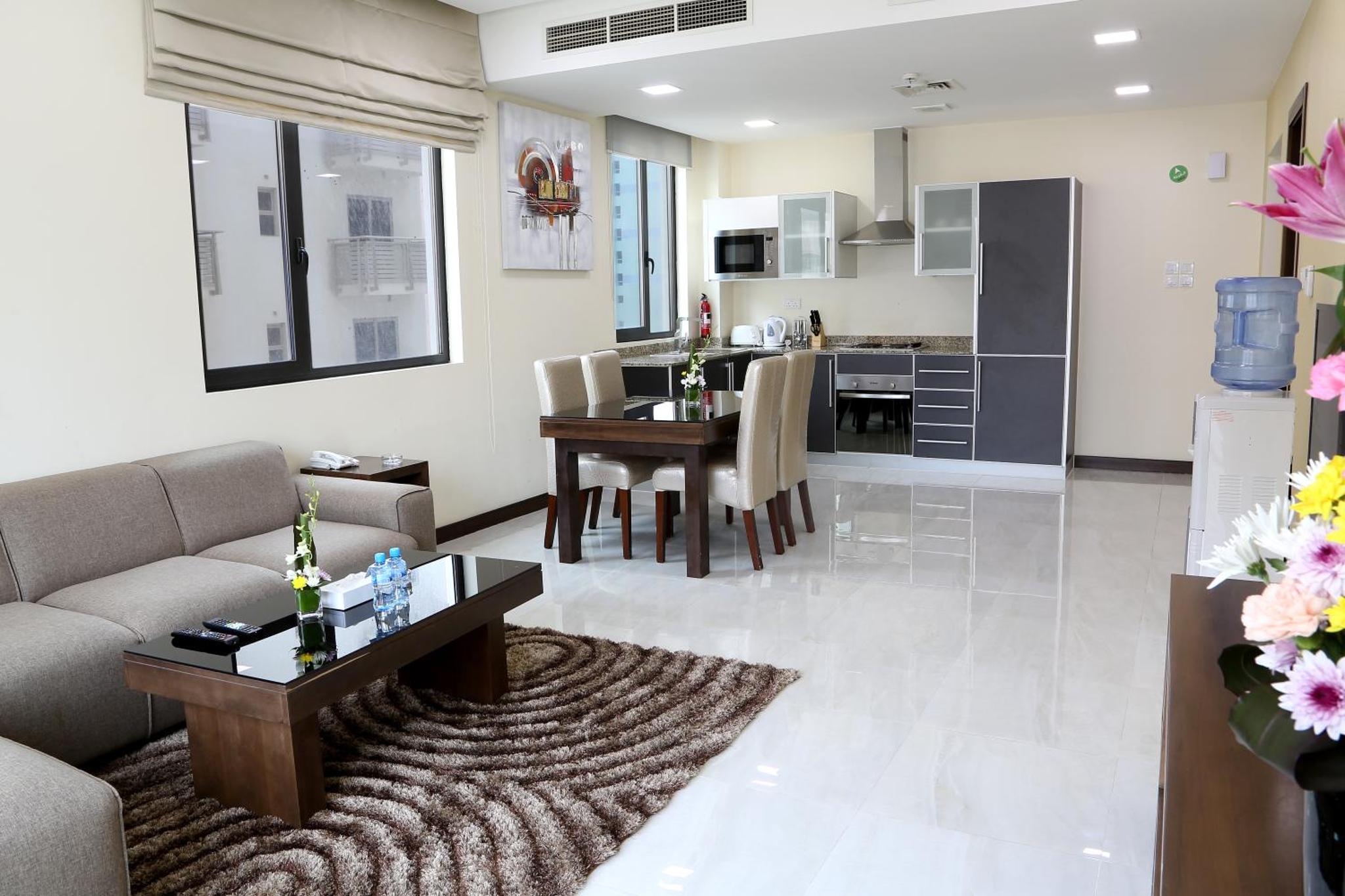 a living room and kitchen with a couch and a table at Belle Tower Apartments in Manama