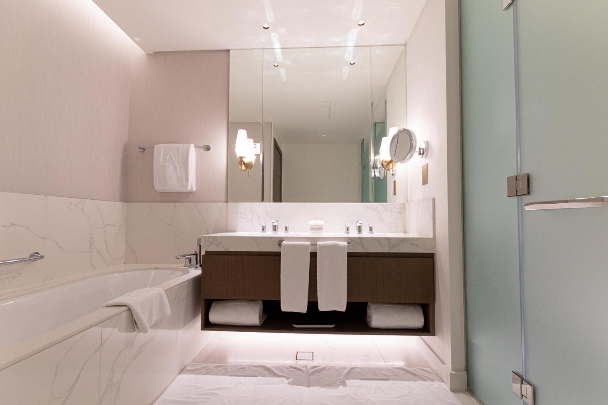 a bathroom with a sink and a tub and a mirror at Premium Apartments at Address Resort Residendtial Building in Muharraq