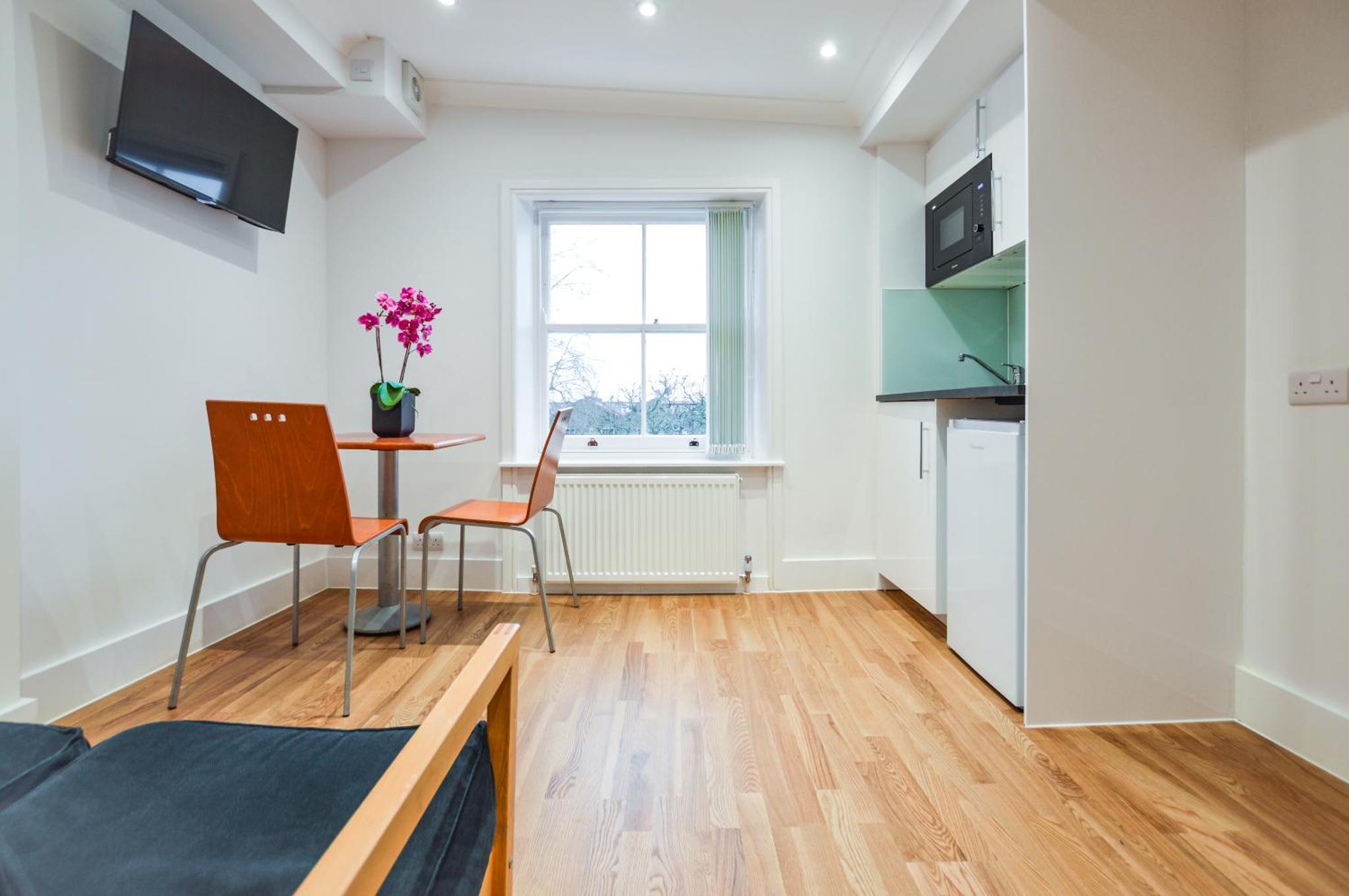 a living room with a table and chairs and a window at Westbourne Crescent Serviced Apartments in London +8 photos