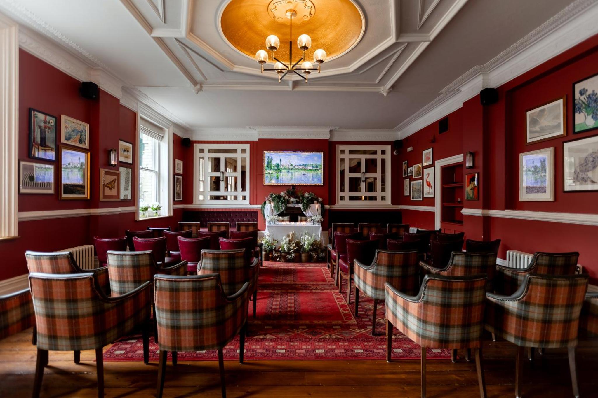 a restaurant with red walls and chairs and a chandelier at The Drayton Court Hotel in London
