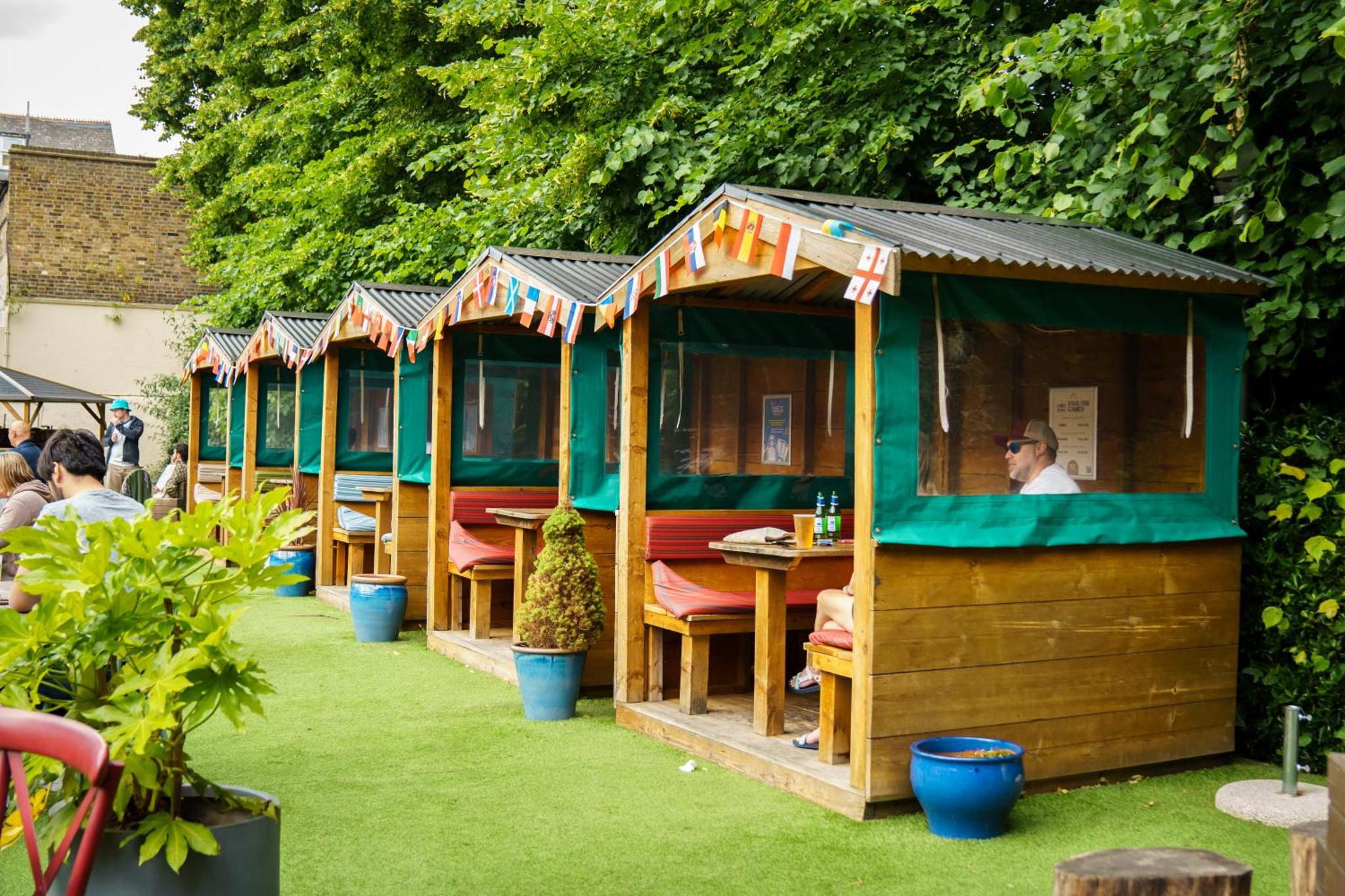 a row of wooden houses with people sitting in them at The Drayton Court Hotel in London +47 photos