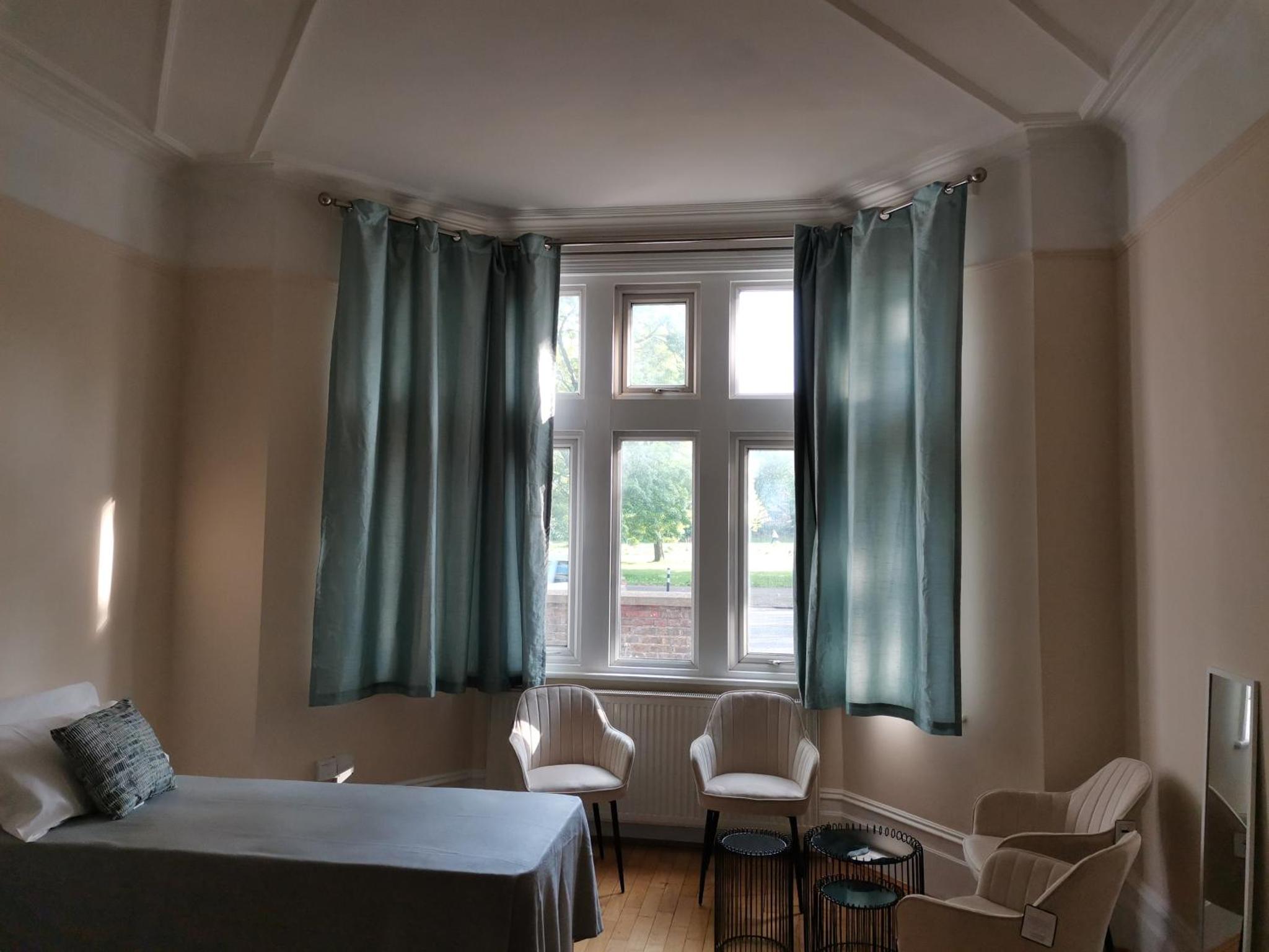 a bedroom with a bed and a window and chairs at Ax 1 Bed and Breakfast in London