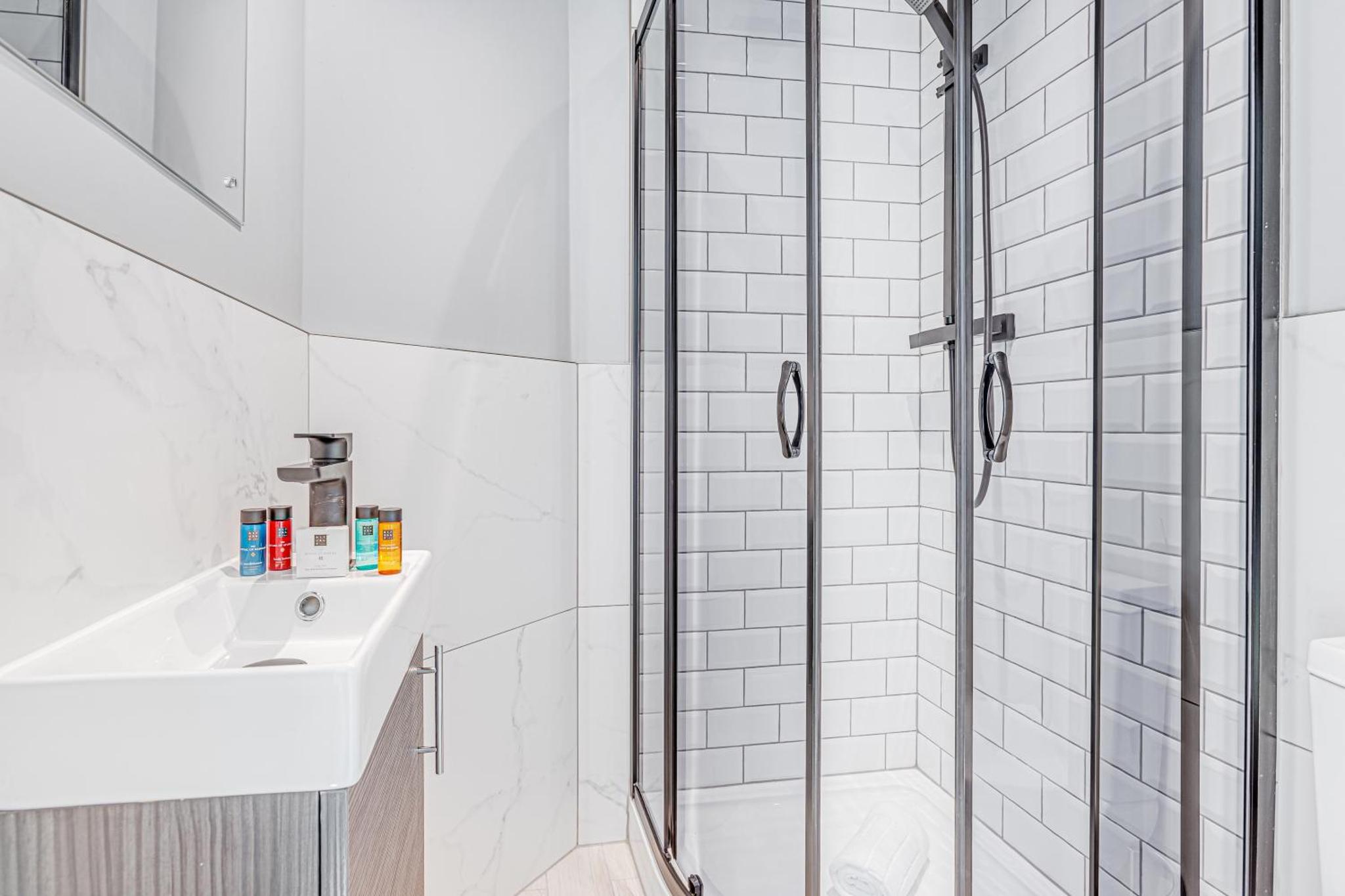 a white bathroom with a shower and a sink at Bob W London Earl's Court - Philbeach Gardens in London