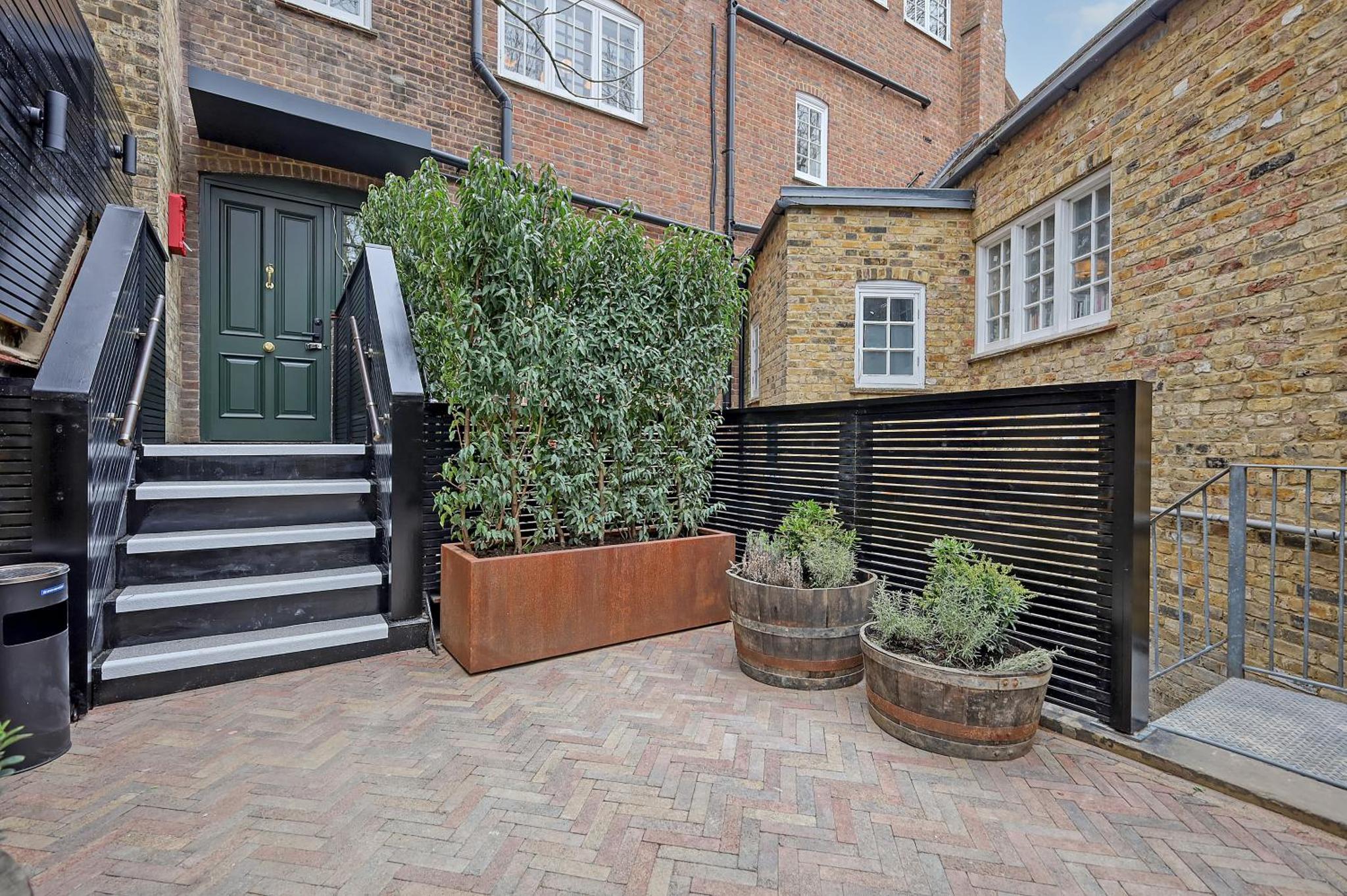 a courtyard with a door and some plants in pots at The Carlton Tavern Hotel in London