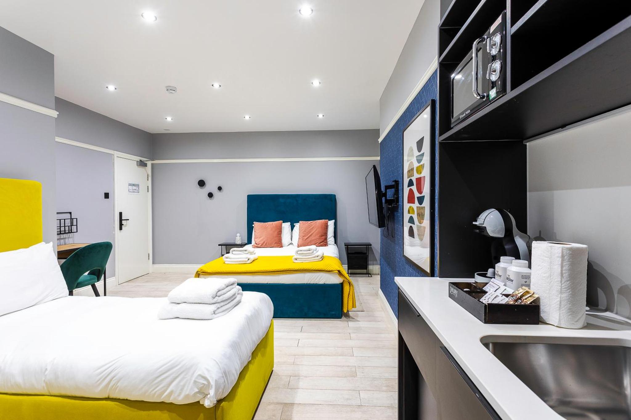 a bedroom with two beds and a sink in a room at Bob W London Earl's Court - Warwick Road in London