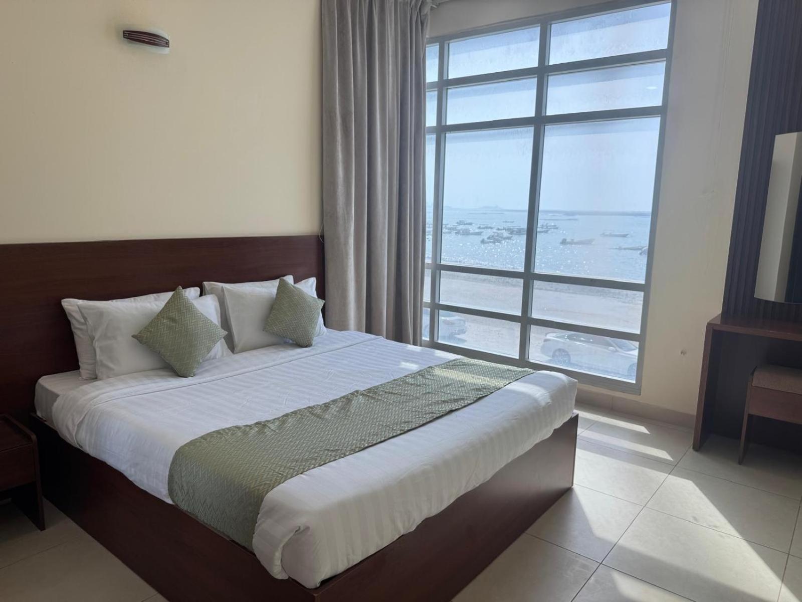 a bedroom with a bed with a large window at Marine Beach Apartment in Seef +30 photos