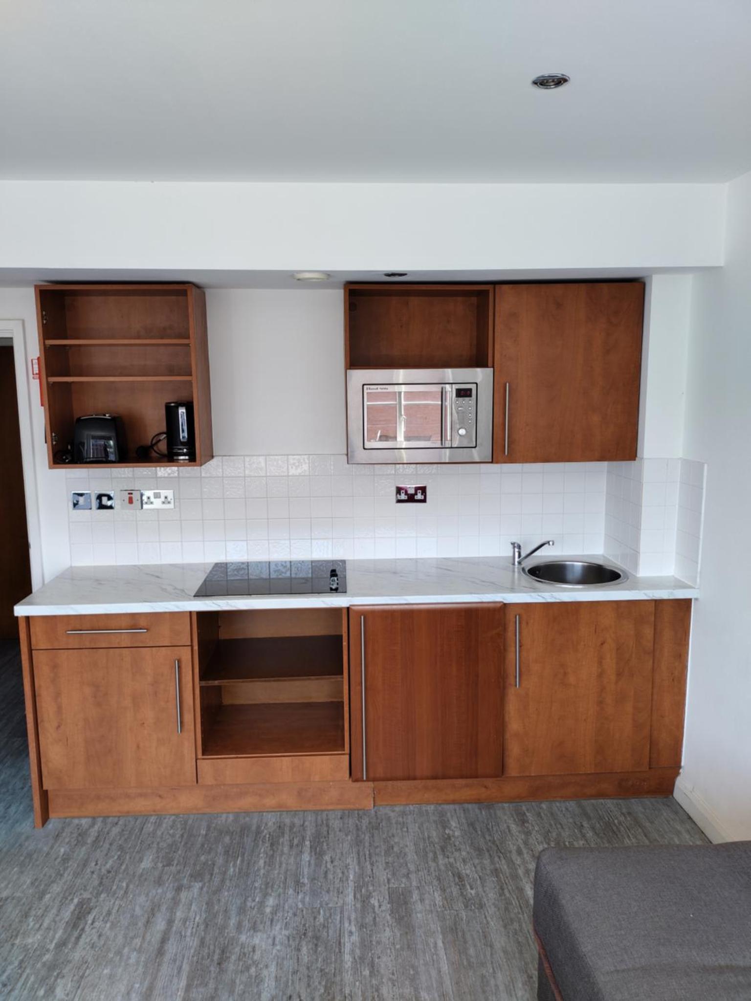 a kitchen with wooden cabinets and a microwave at Roland House in London +14 photos