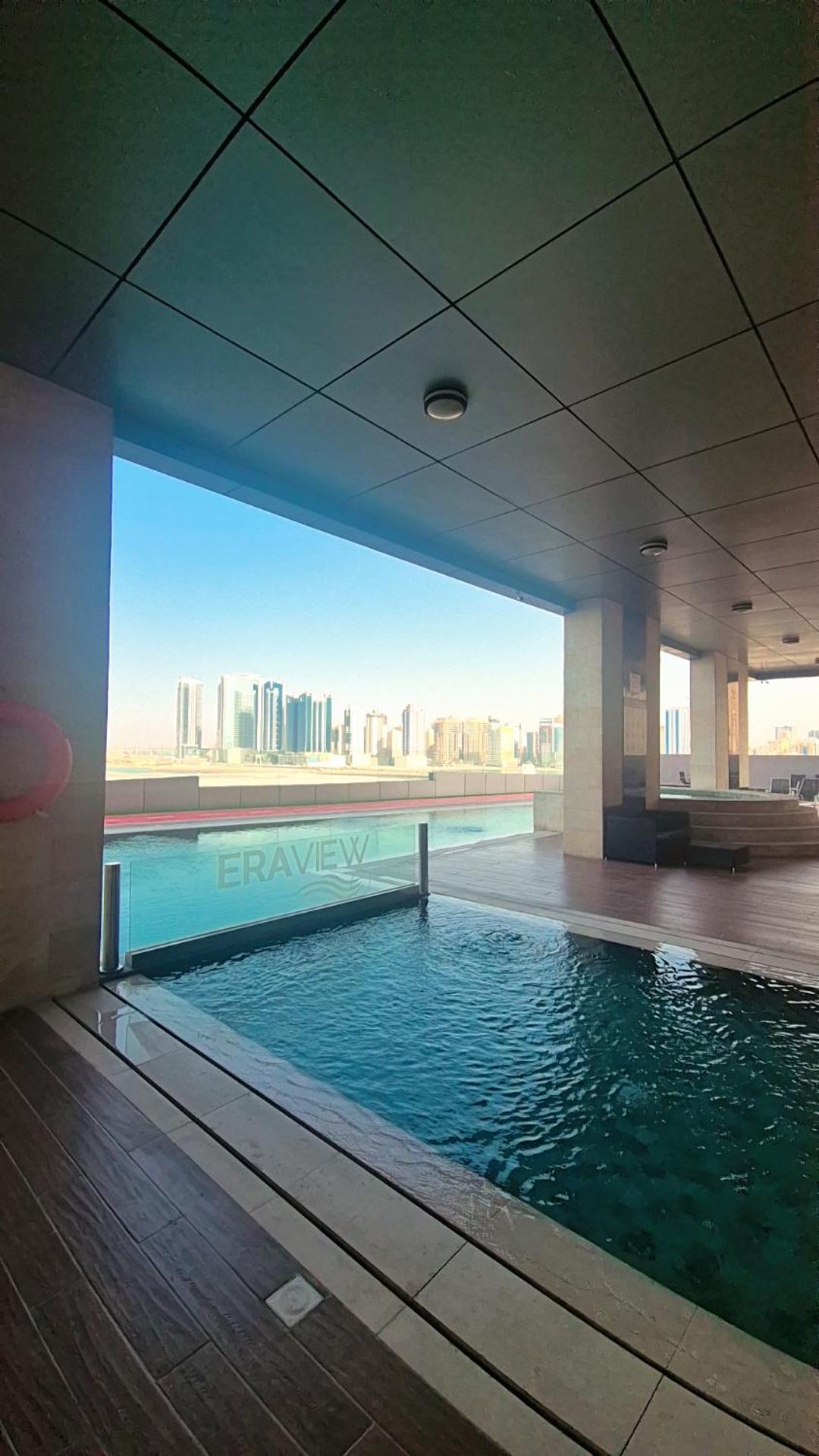 a swimming pool in a building with a view of the city at Luxury Romantic Sea View Apartment-ERAإقامة هادئة إطلالة بحرية موقع استثنائي- Manama in Manama