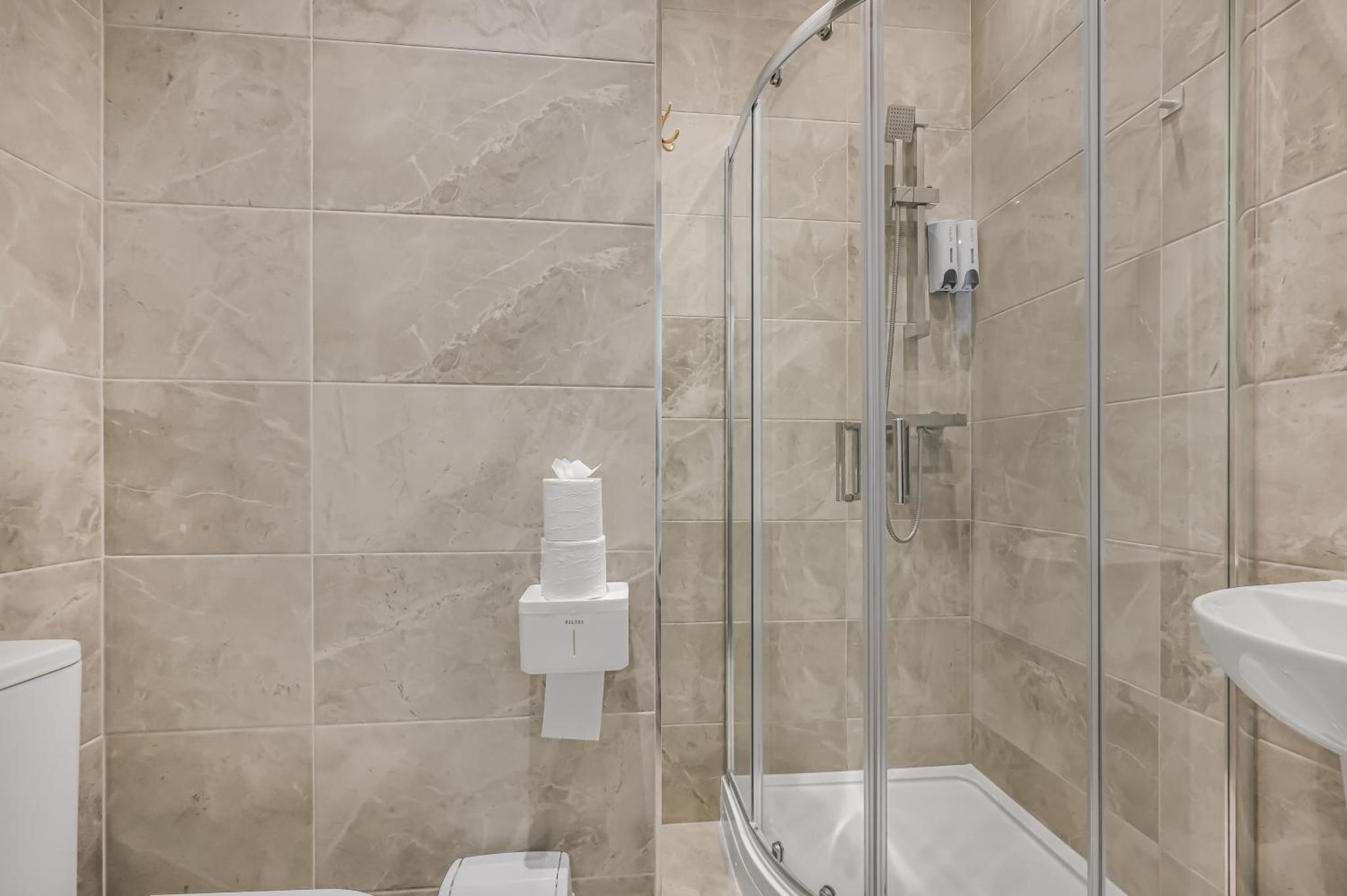 a bathroom with a shower and a toilet and a sink at Studio 64 in London