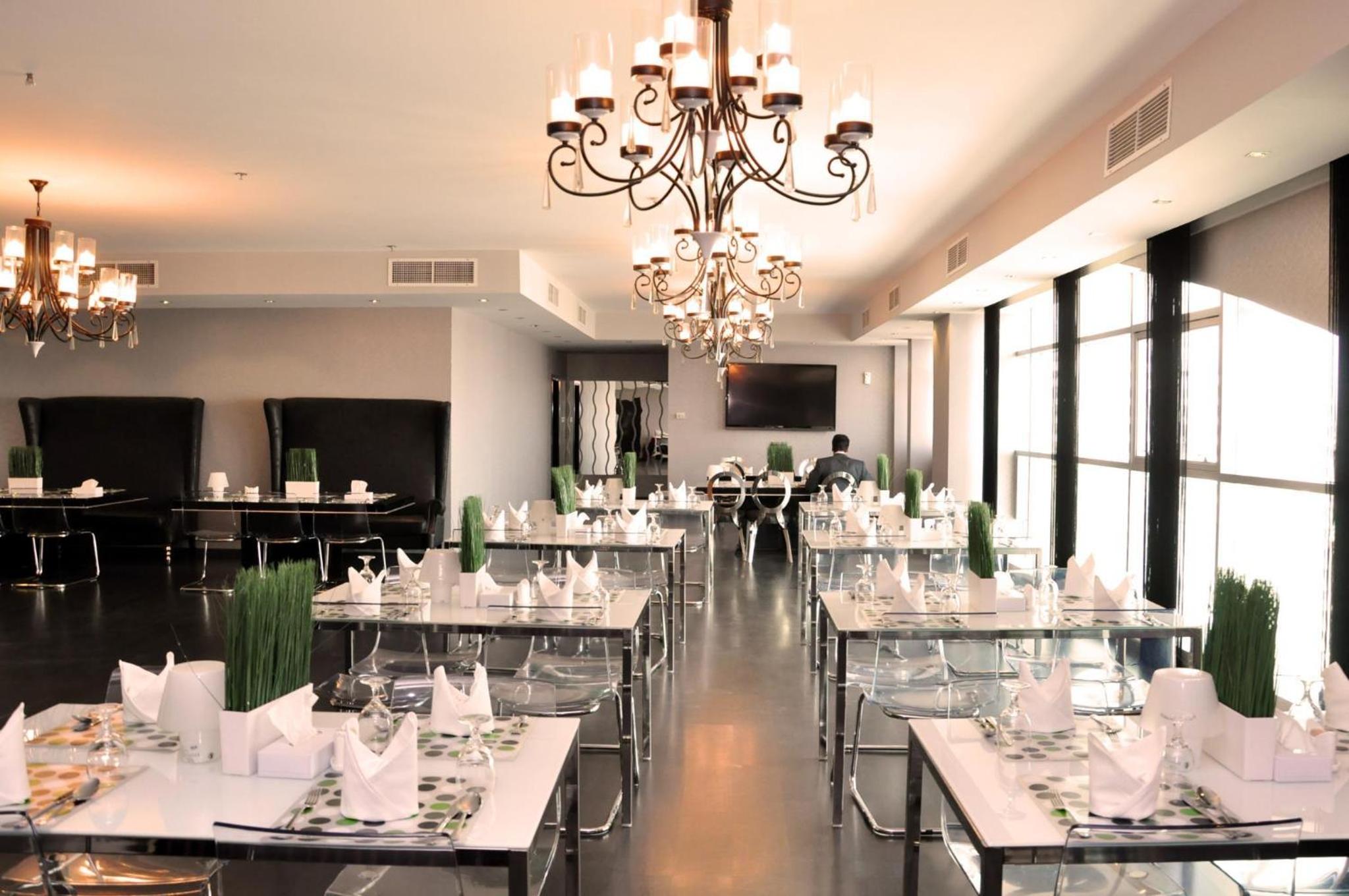 a dining room with tables and chairs and a chandelier at Al Manzil Hotel Bahrain in Juffair