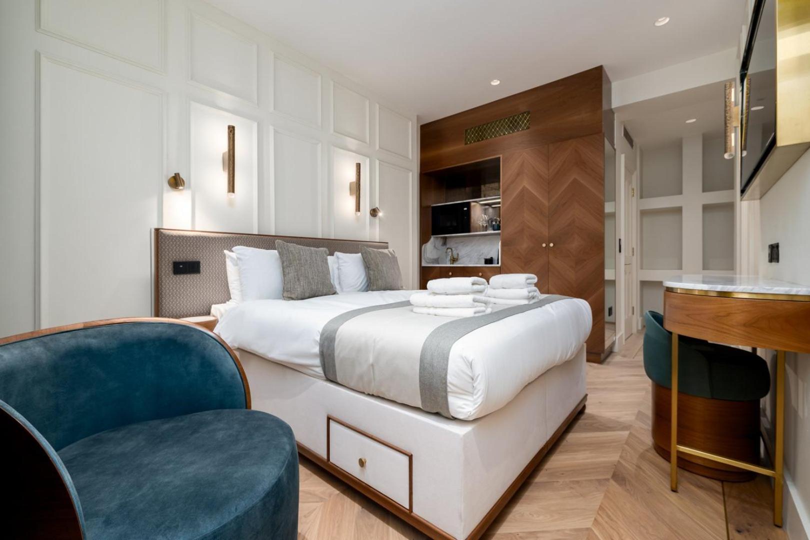 a bedroom with a large white bed and a blue chair at GuestReady - The Fitzroy in London