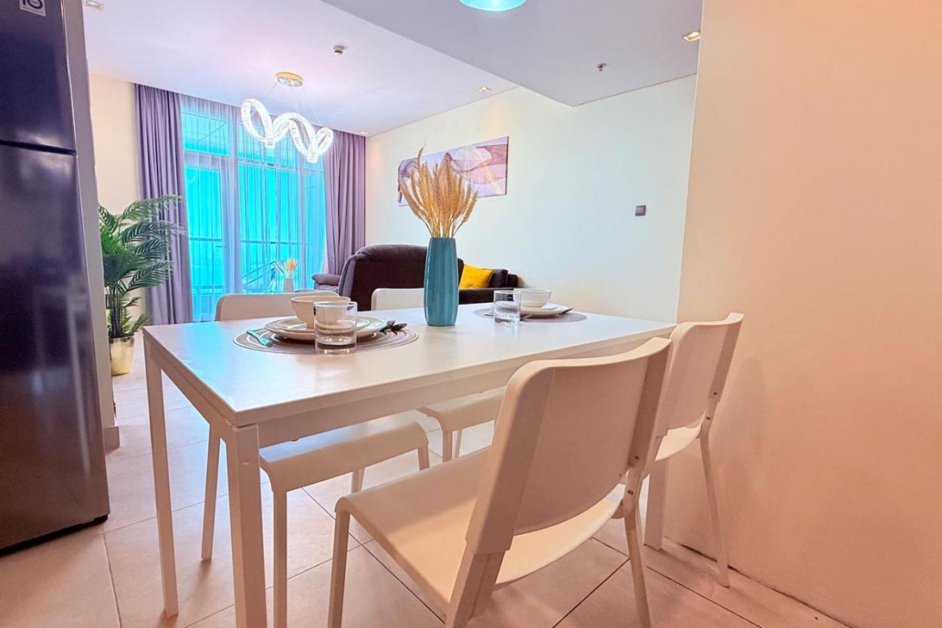 a dining room with a table with chairs and a refrigerator at Seaview White 1Br Balcony in Manama