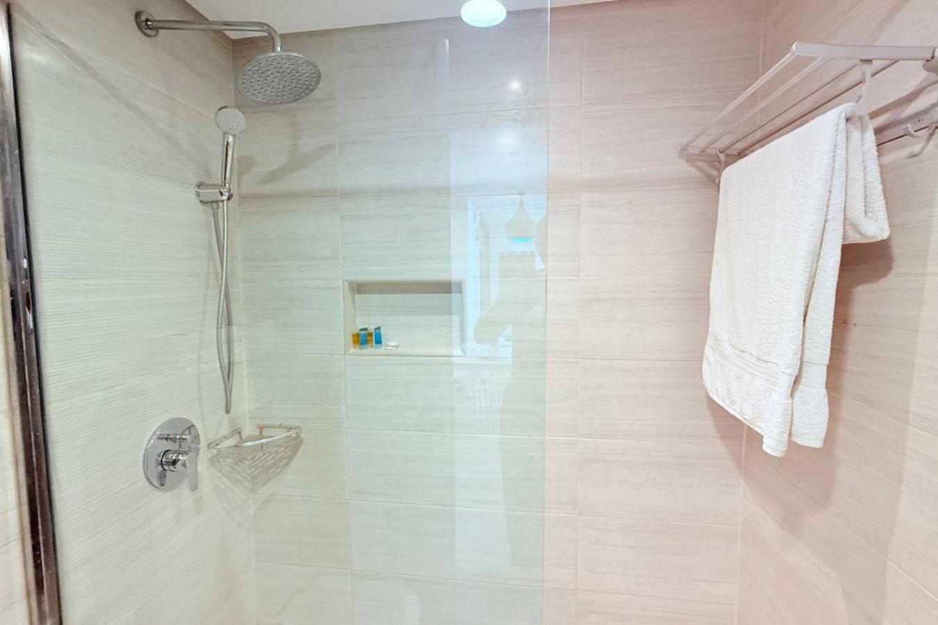 a shower with a glass door in a bathroom at Seaview White 1Br Balcony in Manama